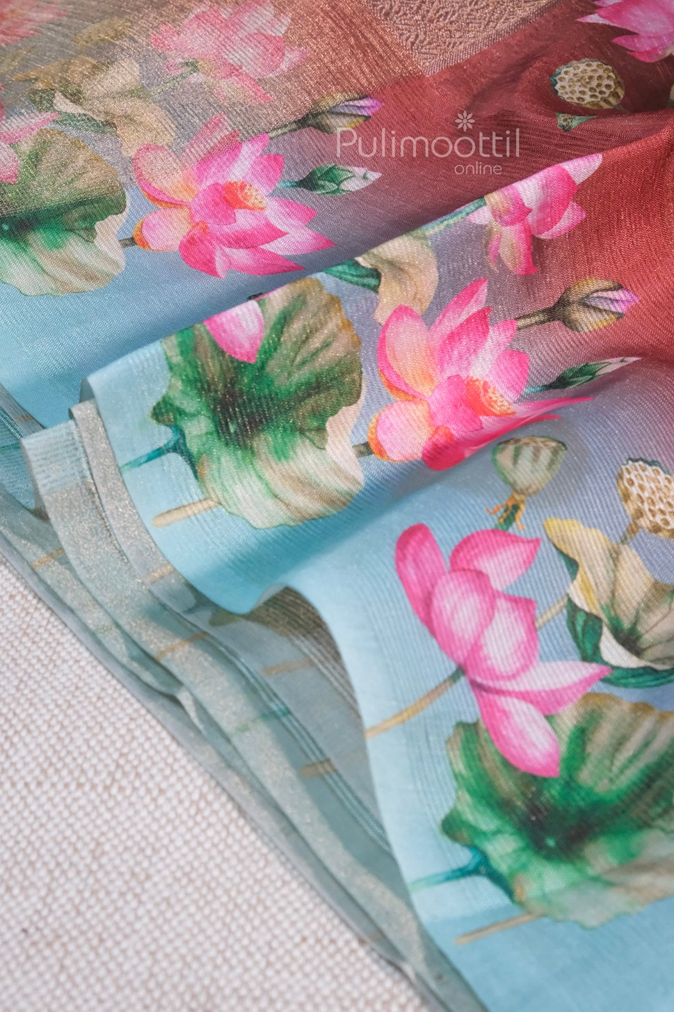 Detailed view of floral printed organza saree section featuring vibrant lotus flowers on a pastel blue base.