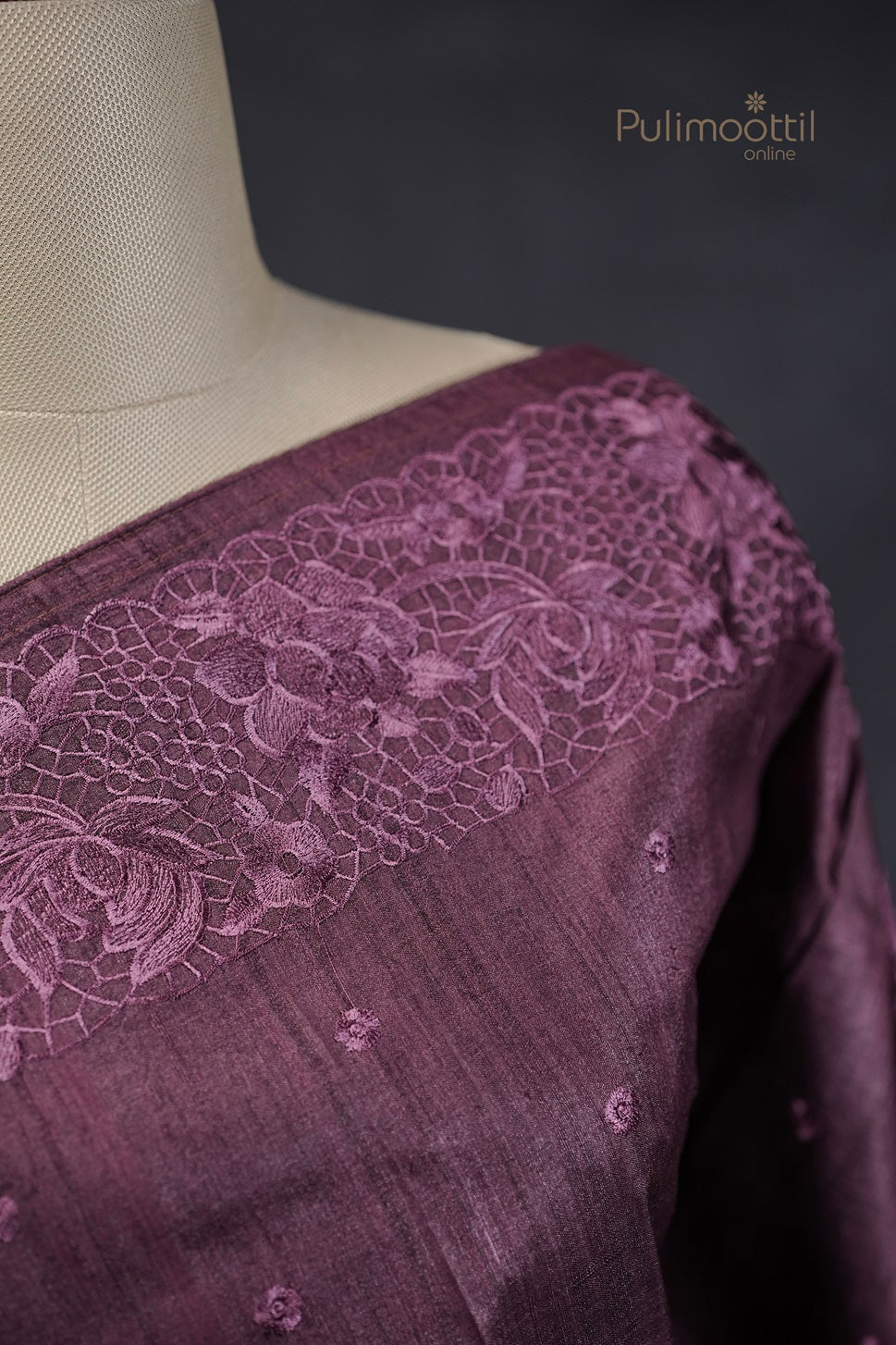 Close-up of the purple saree’s neckline on a mannequin, showcasing the detailed floral lace embroidery.