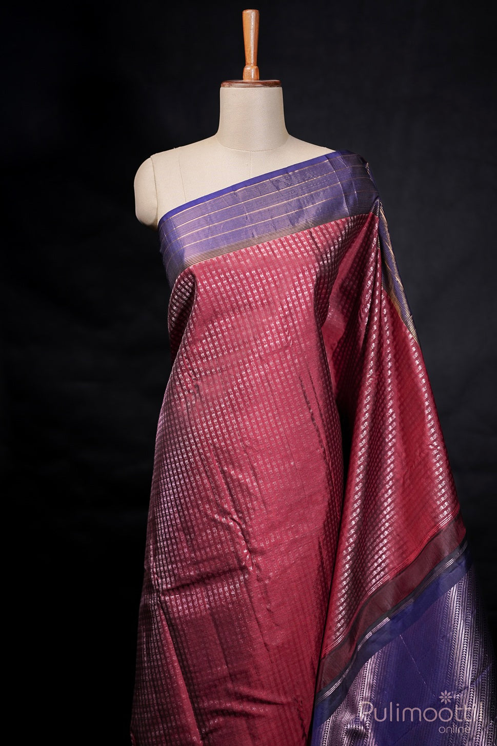 Mannequin draped in maroon Kanchipuram saree with rose gold zari and contrast blue border.
