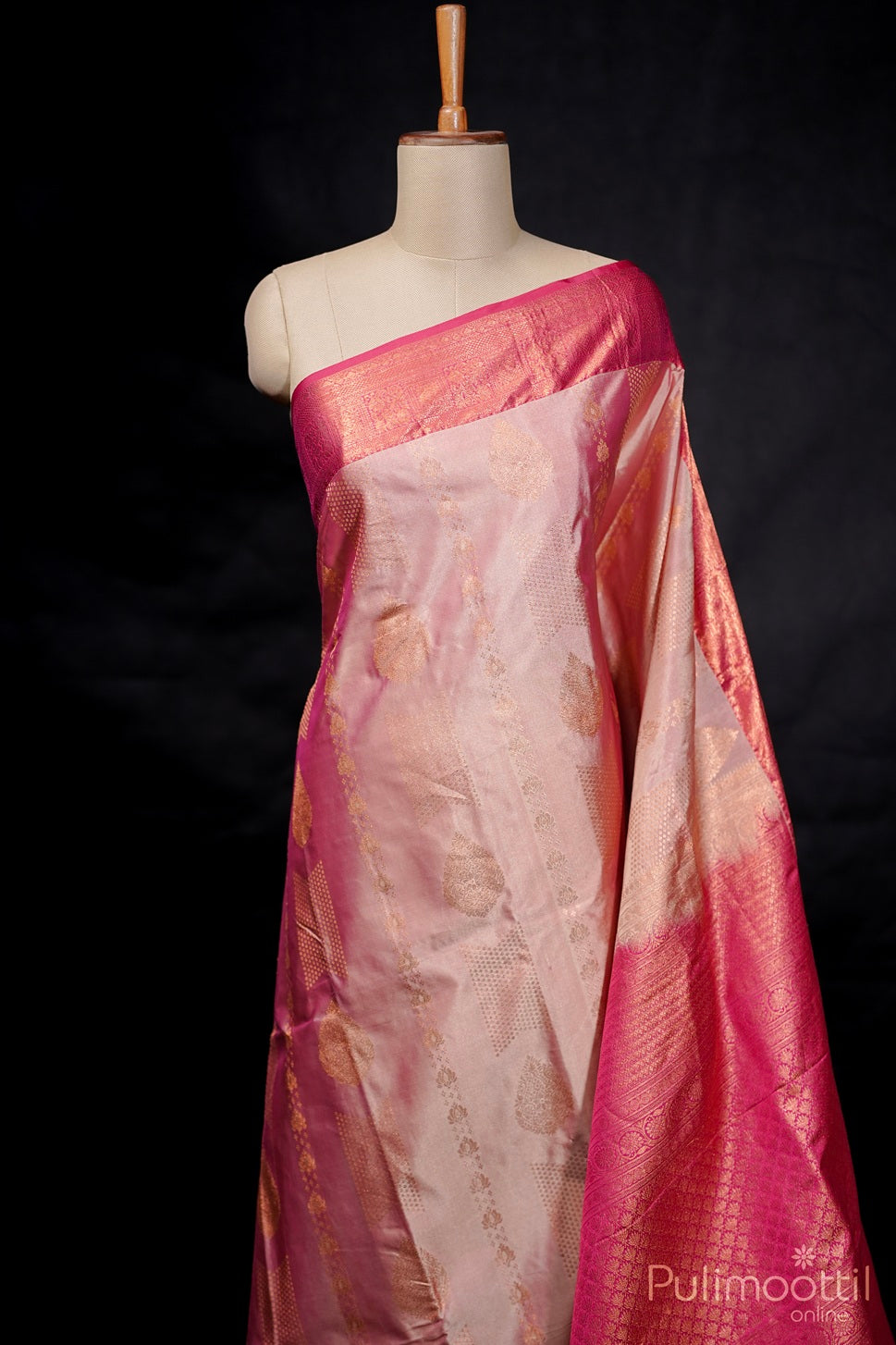 Full view of melon colour semi Kanchipuram saree displayed on mannequin with designer body and contrast border.