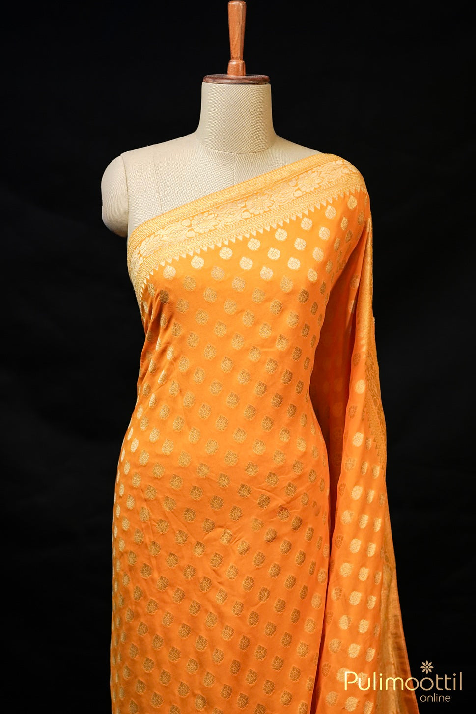 Mustard yellow Banarasi saree with golden buttas and border, draped on mannequin.