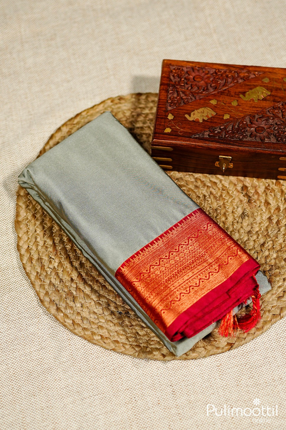 Close view of folded ash Arni silk saree border — red and gold weave design