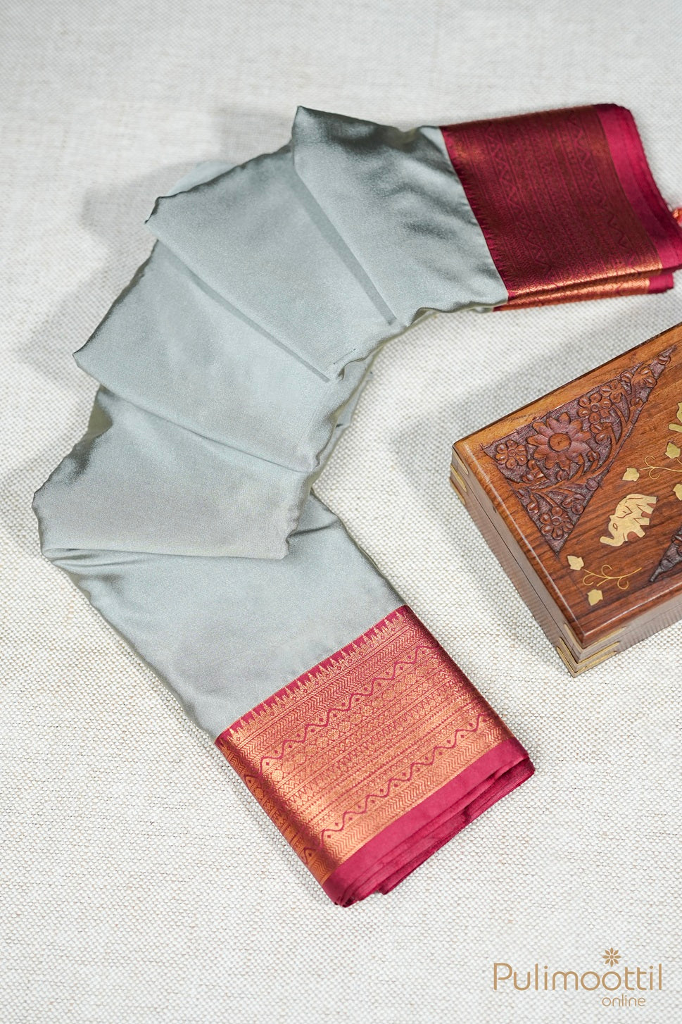 Gray saree with maroon border and wooden box on a light background