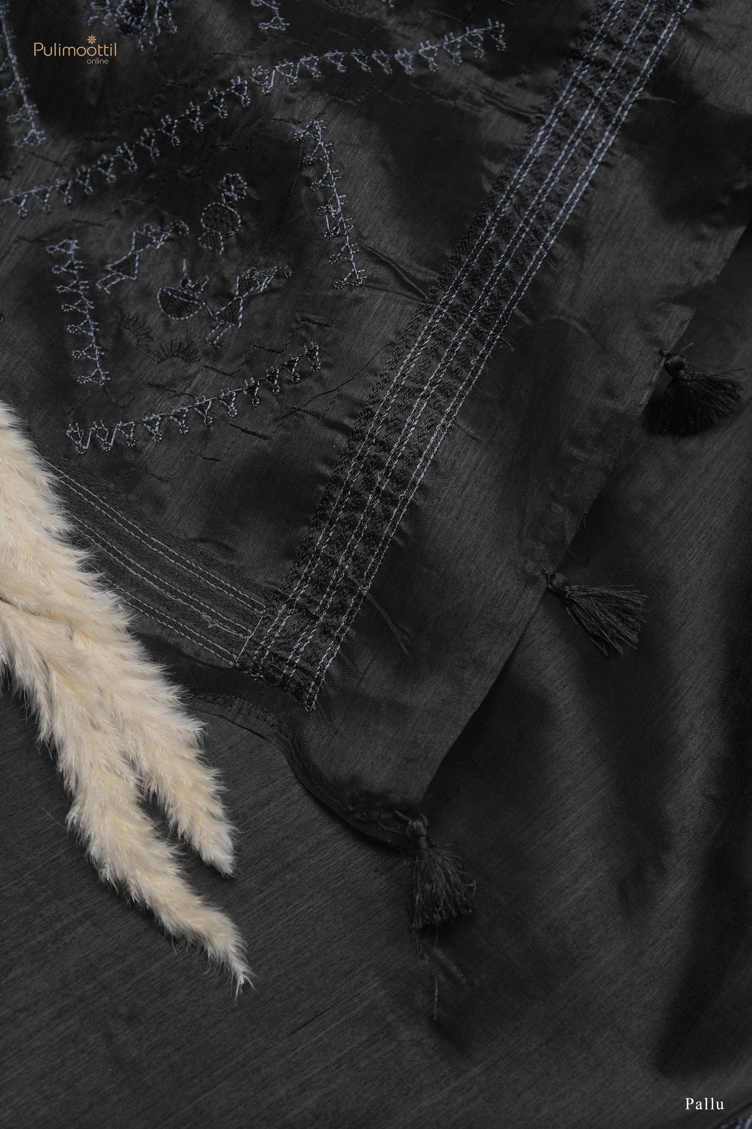 Black saree pallu with tribal embroidery, striped border, and tassel detailing