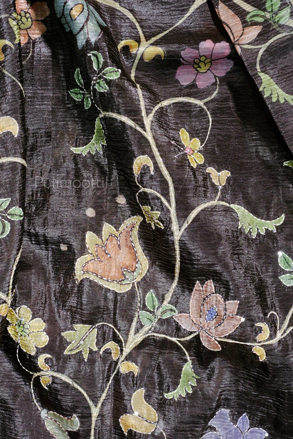 Detailed view of the floral embroidery on a black textured saree, showcasing pastel-colored flowers and vines.