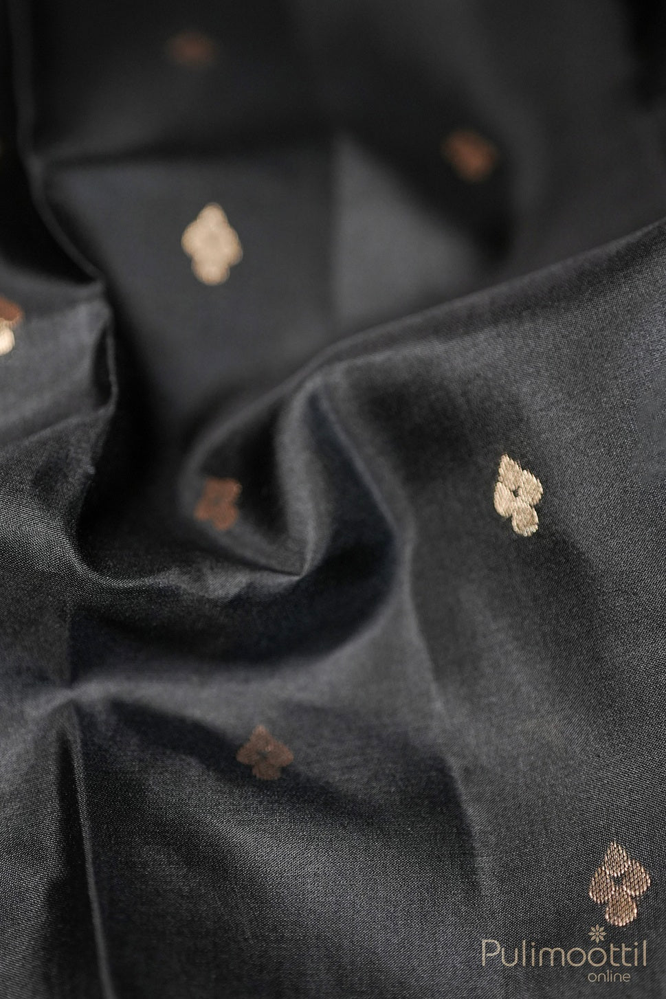 Close-up of golden buttas on black Kanchipuram soft silk saree fabric