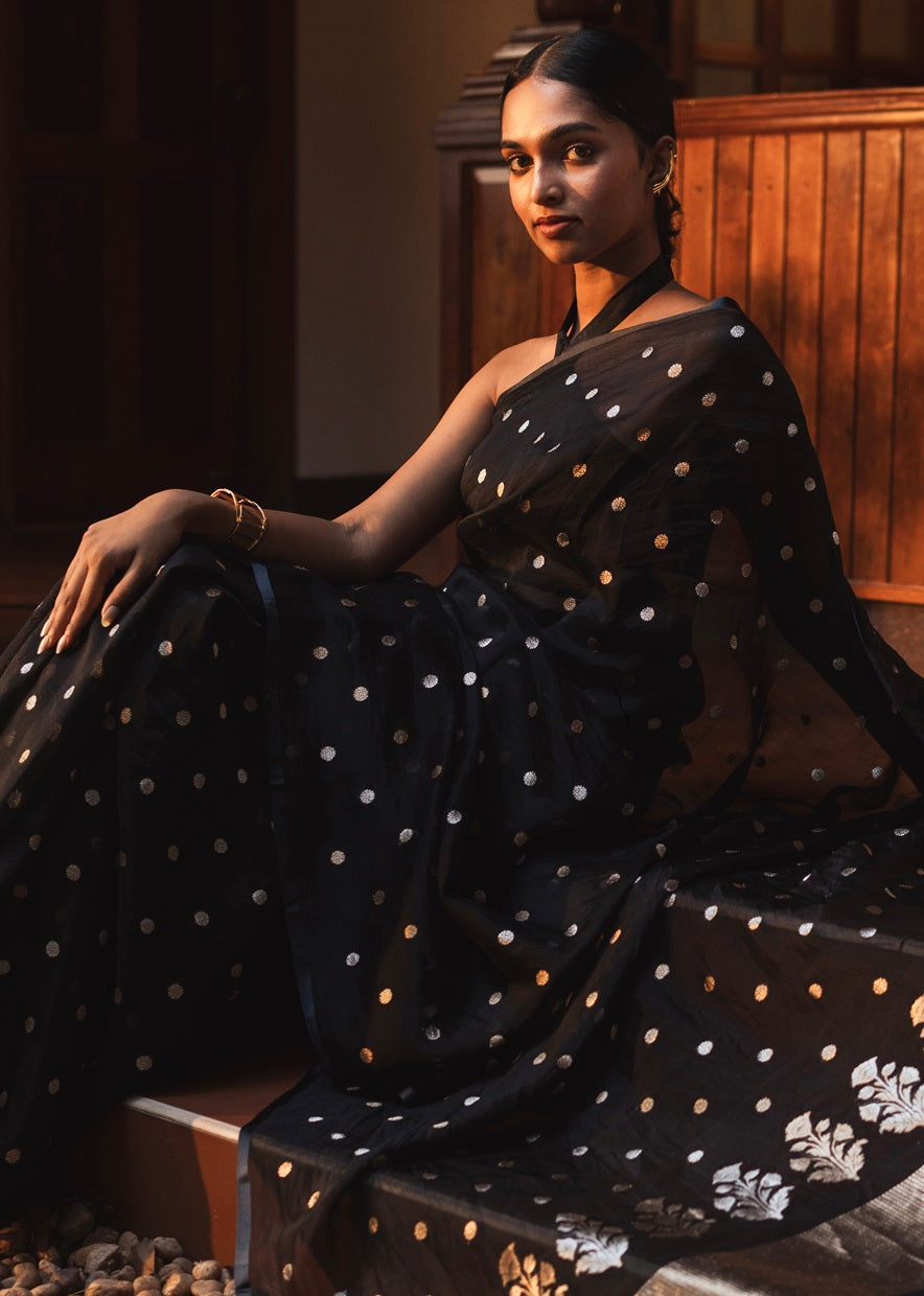 Woman wearing black organza saree with golden and silver zari butta work and plain border - elegant draping style