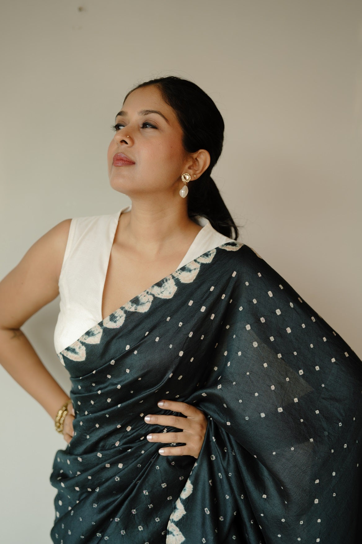 Woman wearing black and white pure tussar bandhini saree with polka dot pattern and decorative white border trim
