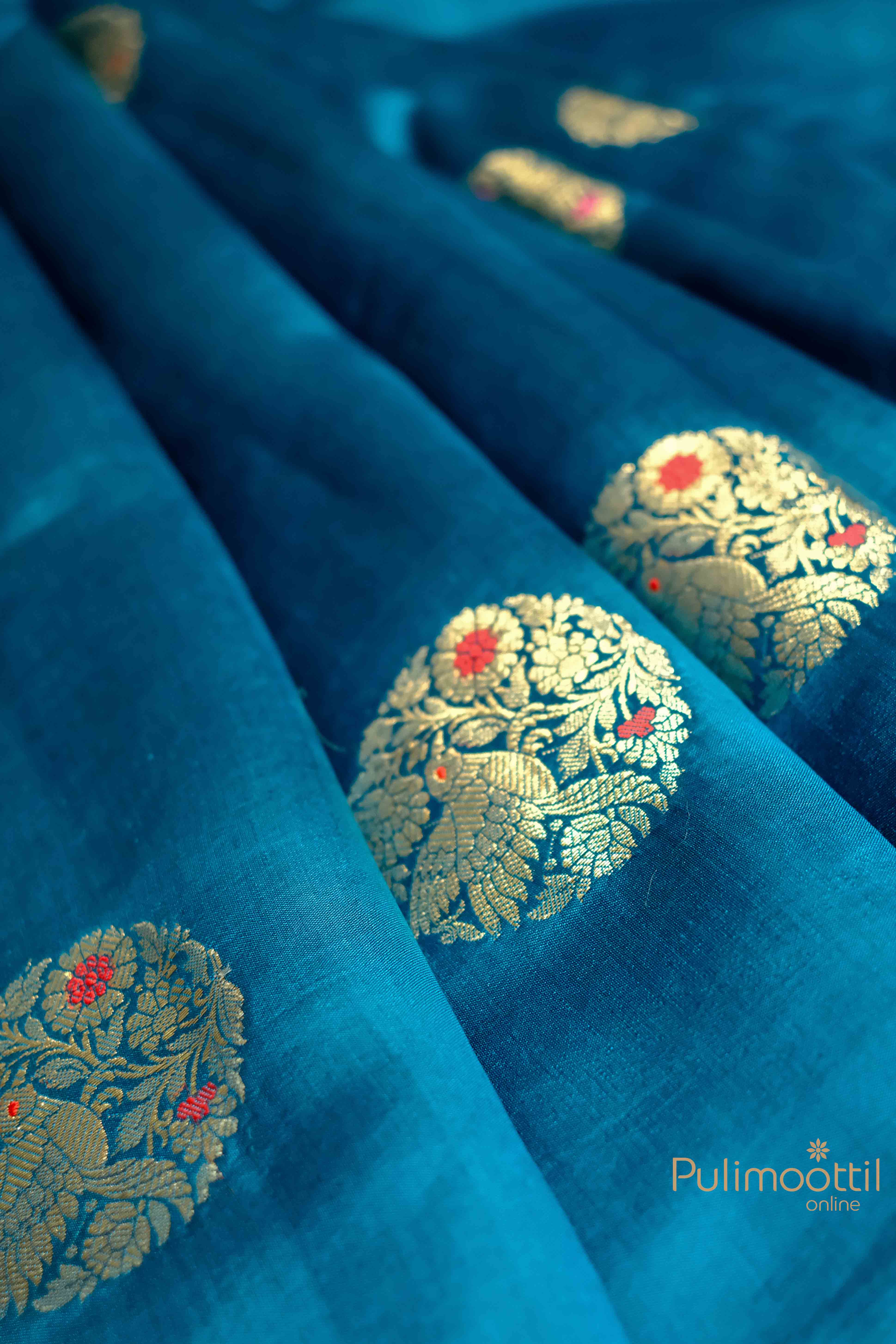 Close-up of light golden floral motifs on the blue Chiniya Silk Saree.