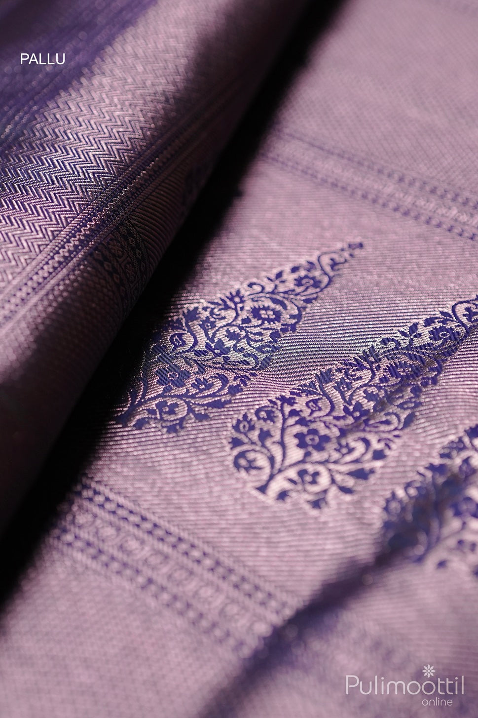 Close-up of blue brocade saree pallu with rose gold zari floral motifs and ornate border design.
