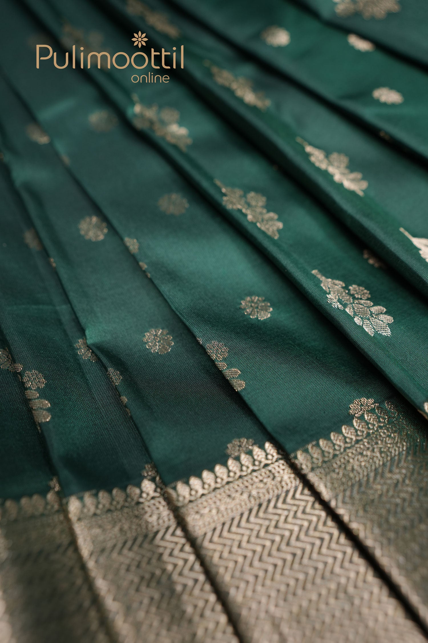 Pleated bottle green Kanchipuram silk saree with golden floral buttas and detailed zari border – traditional bridal and festive wear fabric by Pulimoottil Online