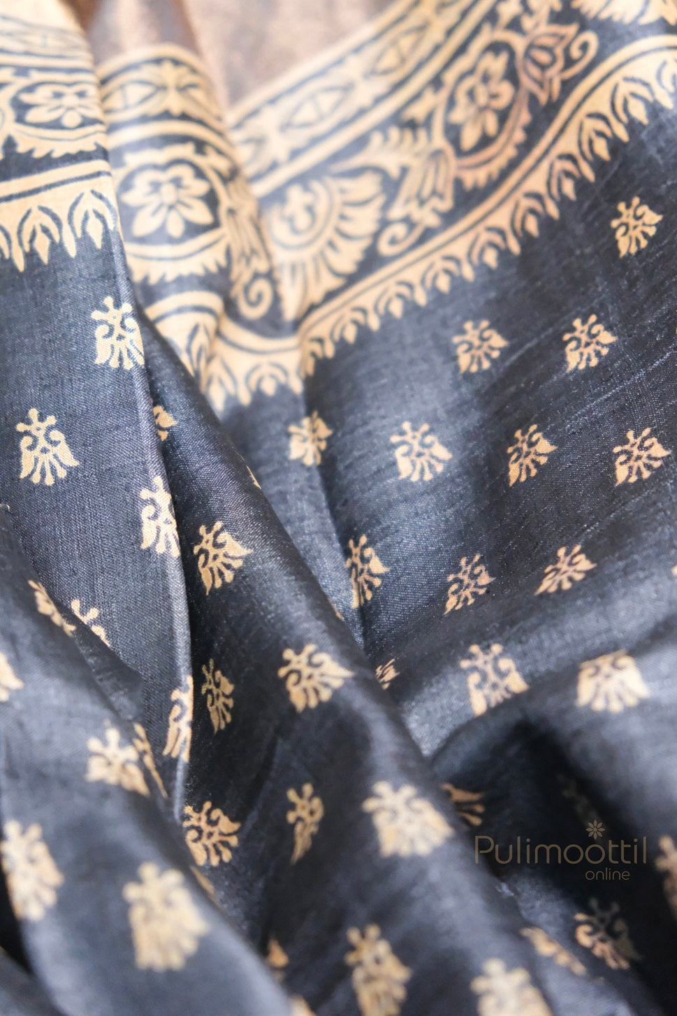 Elegant black cotton silk saree with golden zari floral motifs and intricately woven ornamental border, reflecting traditional Indian design.