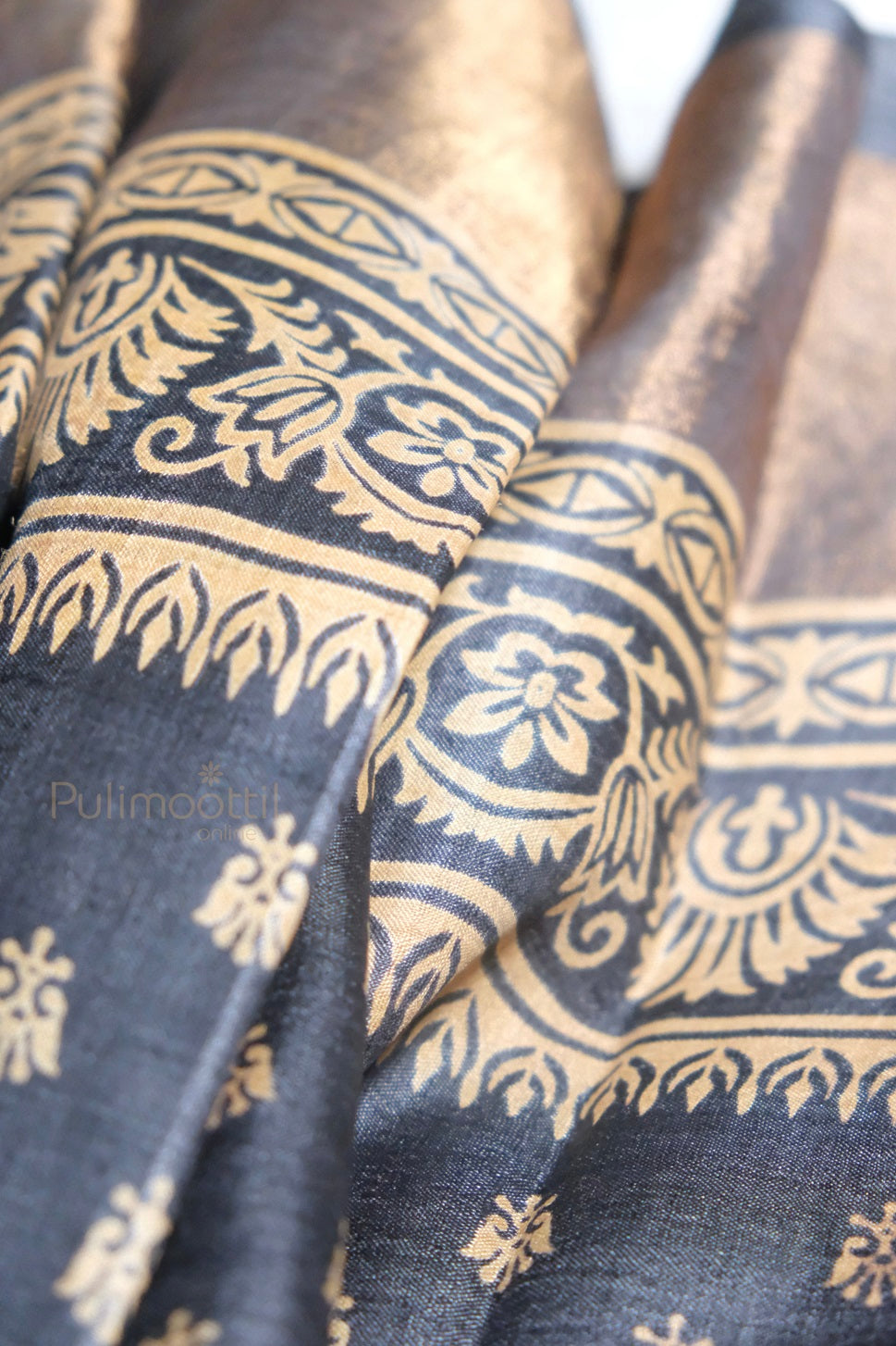 Black cotton silk saree with rich golden zari floral and vine motifs on the pallu and border, showcasing traditional South Indian craftsmanship.