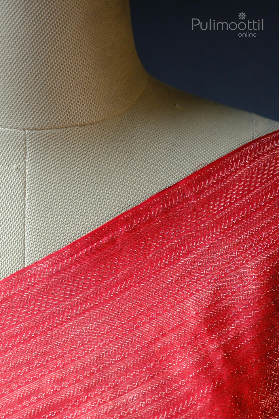 Close-up view of the chilly red Kanchipuram silk saree with intricate zari weaving zig-zag design along the edge.