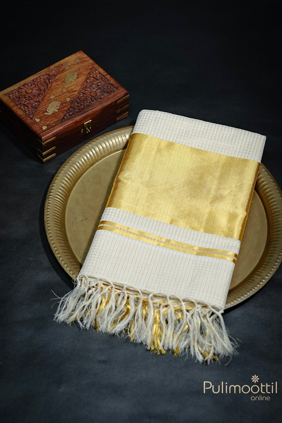 Folded Cream Colour Kerala Traditional Handloom Saree with golden zari check design and tissue border, neatly placed on a decorative plate.