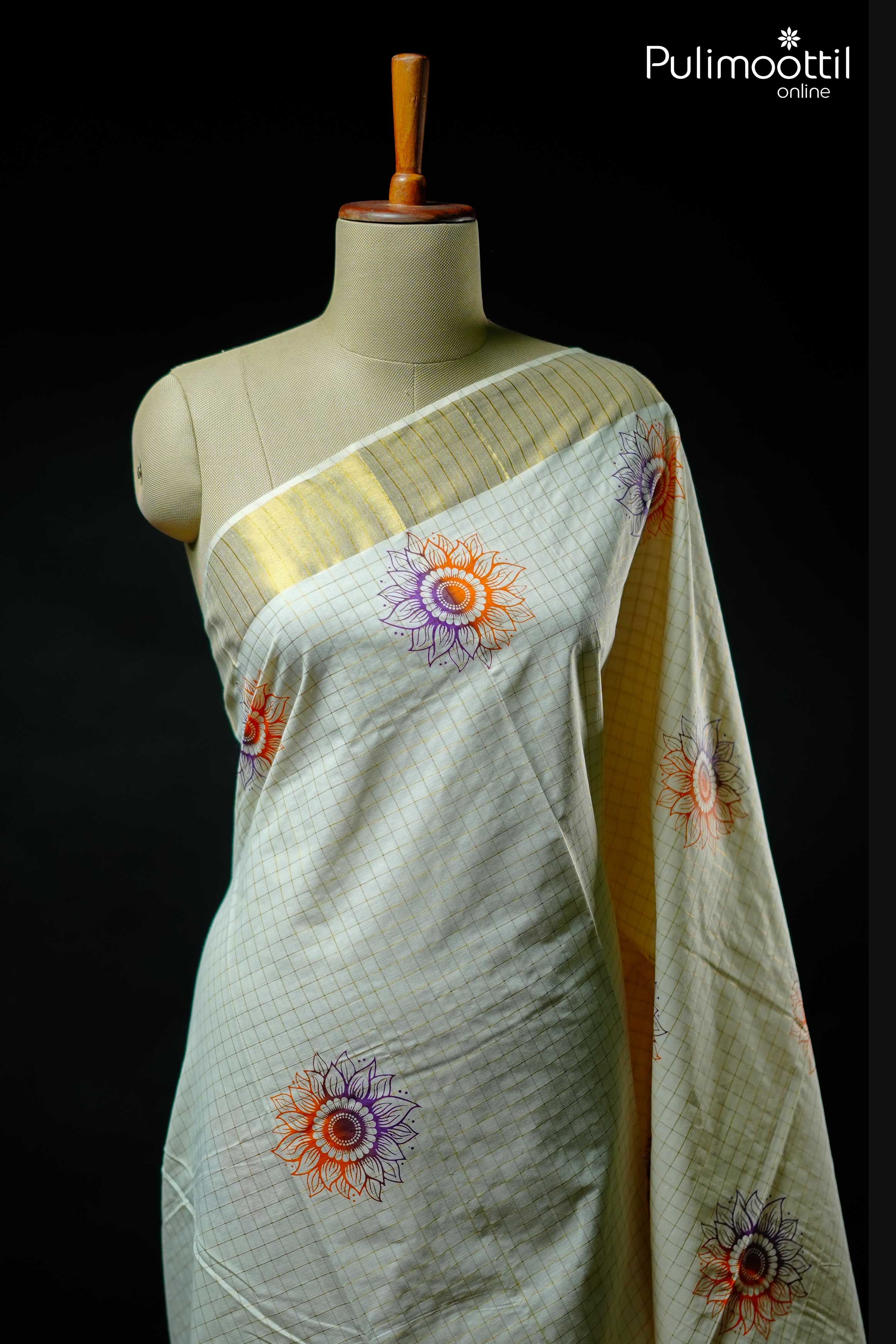 Cream Kerala kasavu saree with golden zari checks, orange and purple floral motifs, and tissue border – displayed on mannequin for Onam collection.