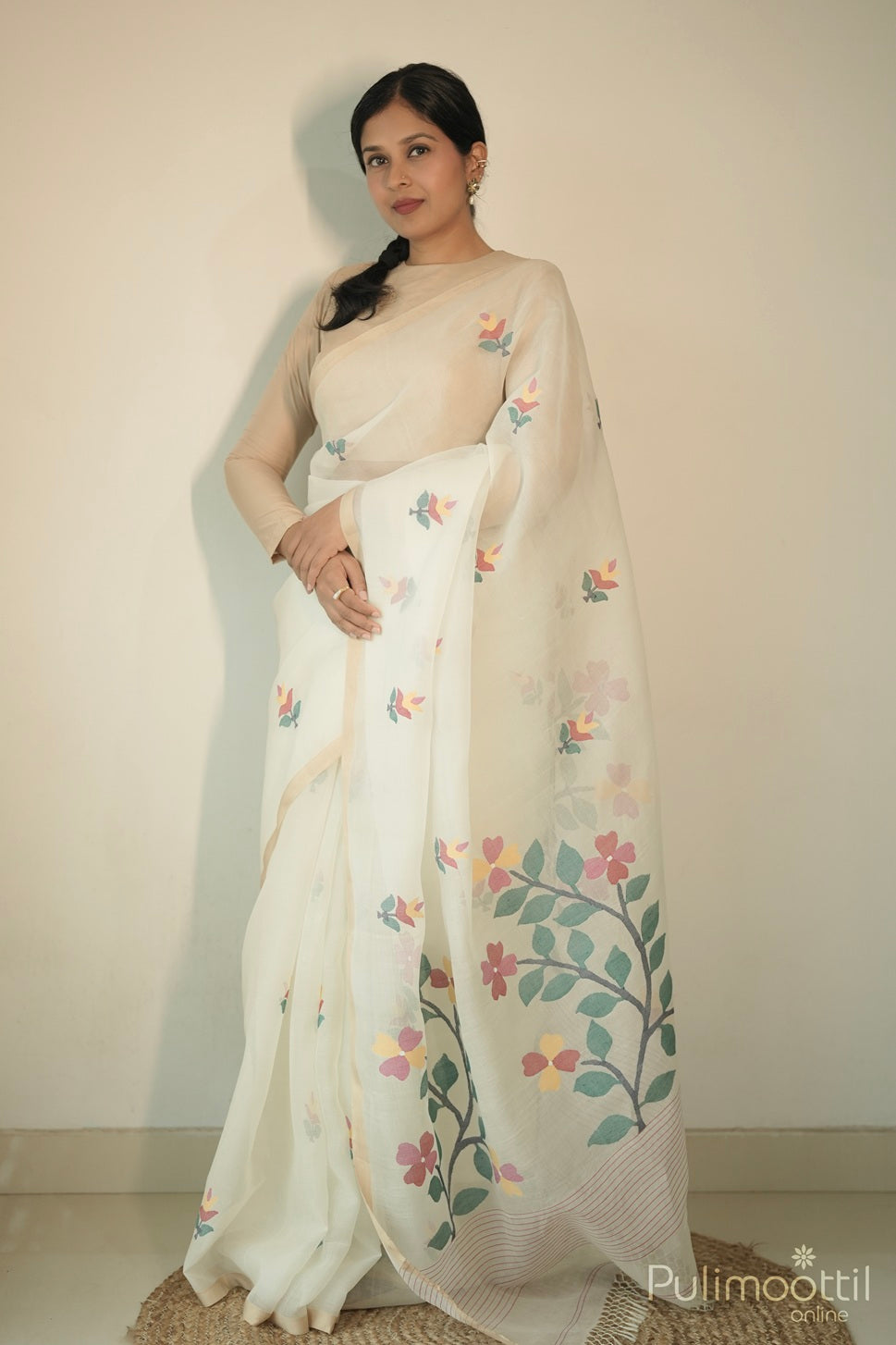 Woman wearing cream organza Jamdhani saree with floral motifs, small border, and striped pallu with tassels.