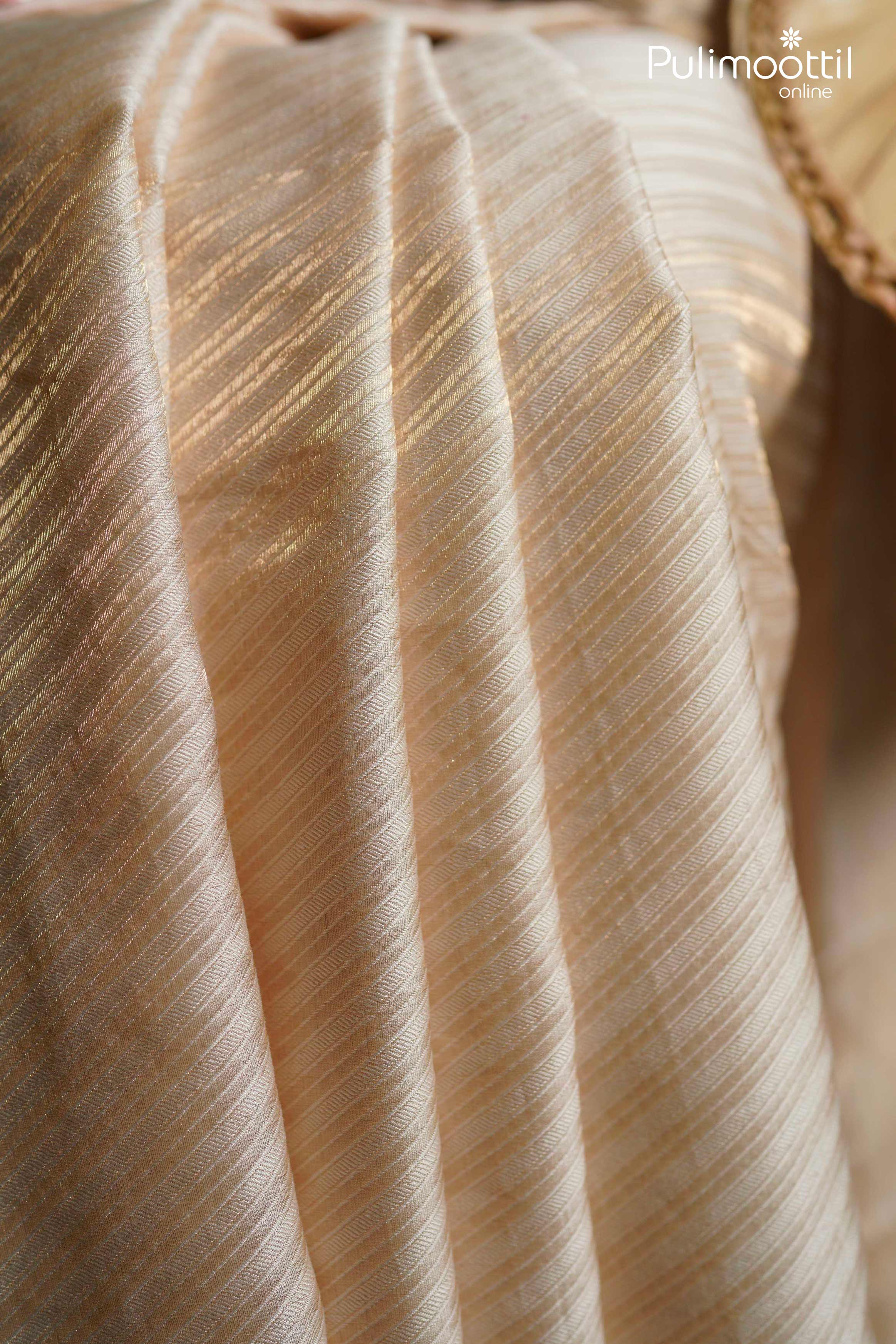 Close-up of cream and gold lightweight brocade saree fabric with diagonal woven pattern, traditional Kerala saree design.