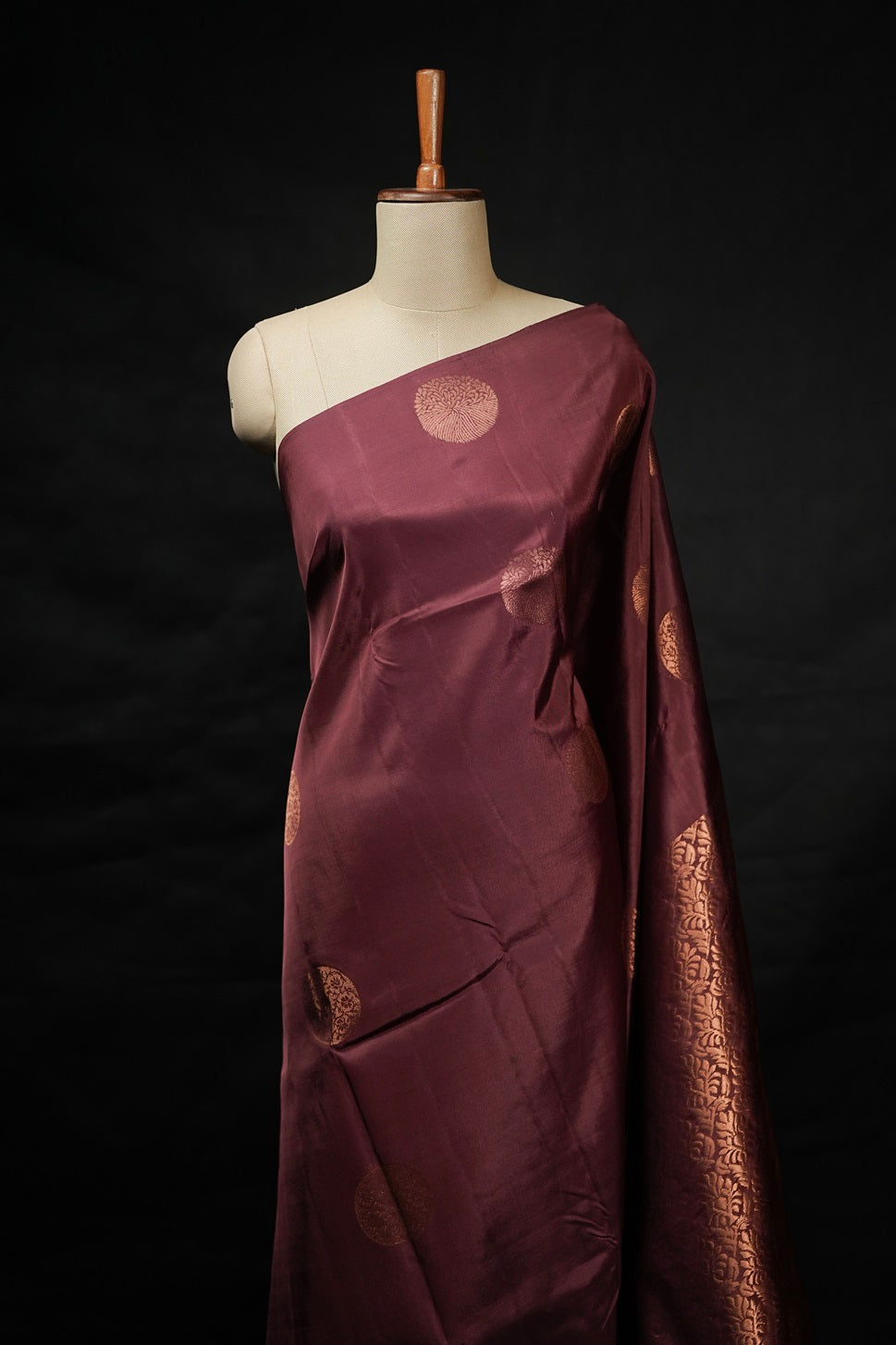 Terracotta color Kanchipuram saree with copper round buttas on body draped on mannequin