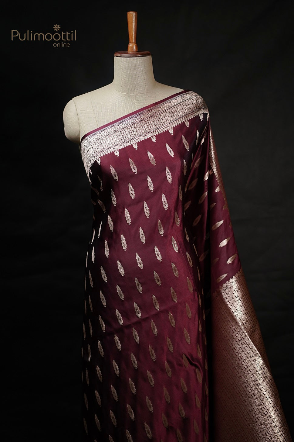 Maroon Mashru silk Banarasi saree draped on mannequin featuring golden buttas on body and intricate designer border, perfect for wedding saree and bridal saree occasions from Pulimoottil Silks.