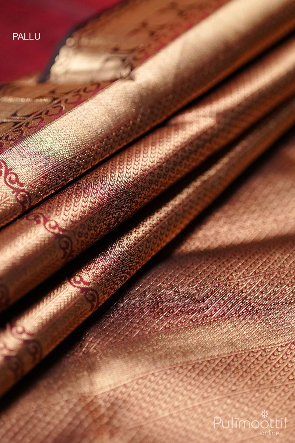 Close-up of golden zari woven pallu on dark maroon Kanchipuram silk saree with intricate detailing