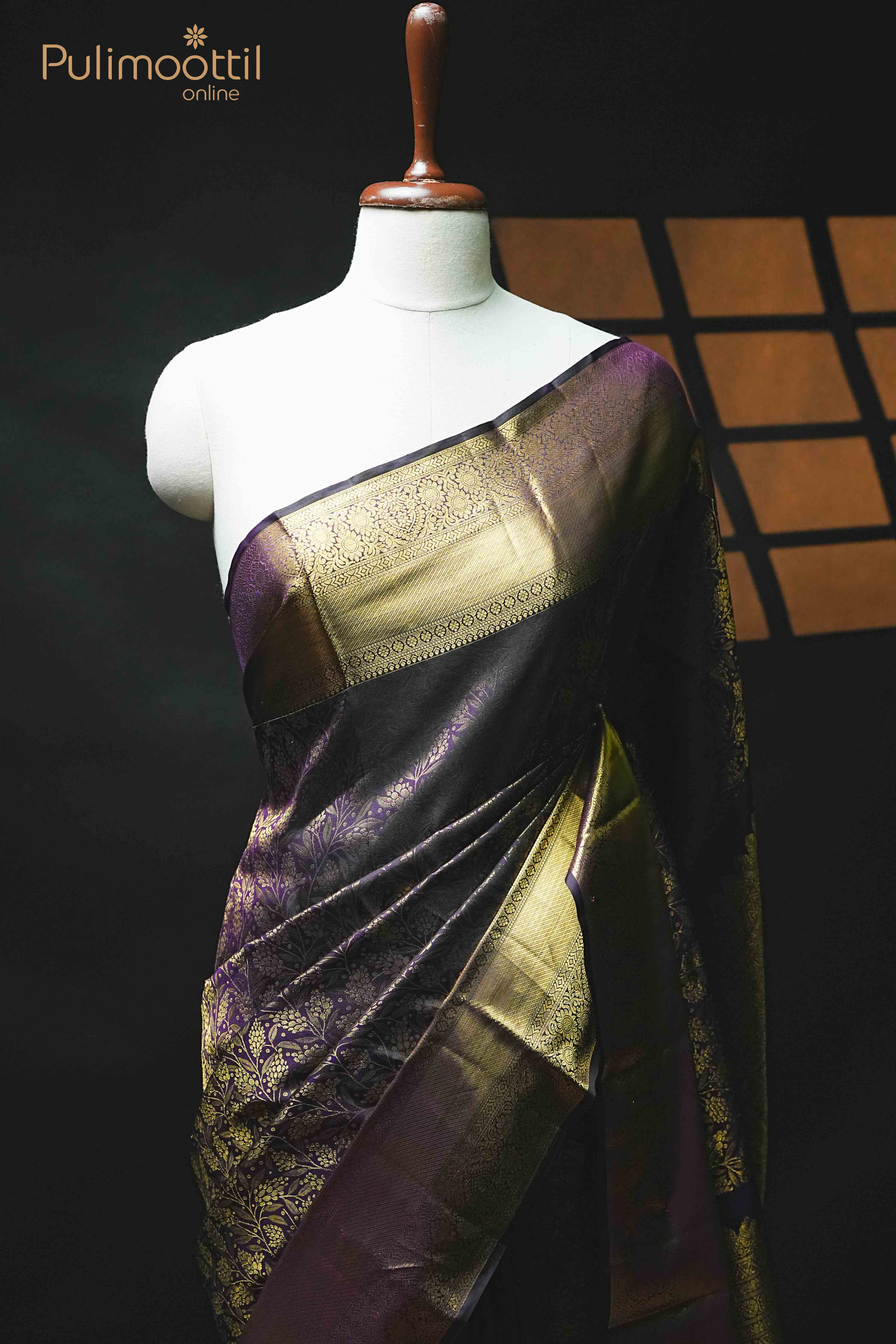 Dark purple pure Kanchipuram silk saree with intricate gold floral brocade and traditional gold zari border, displayed on a mannequin against a dark background