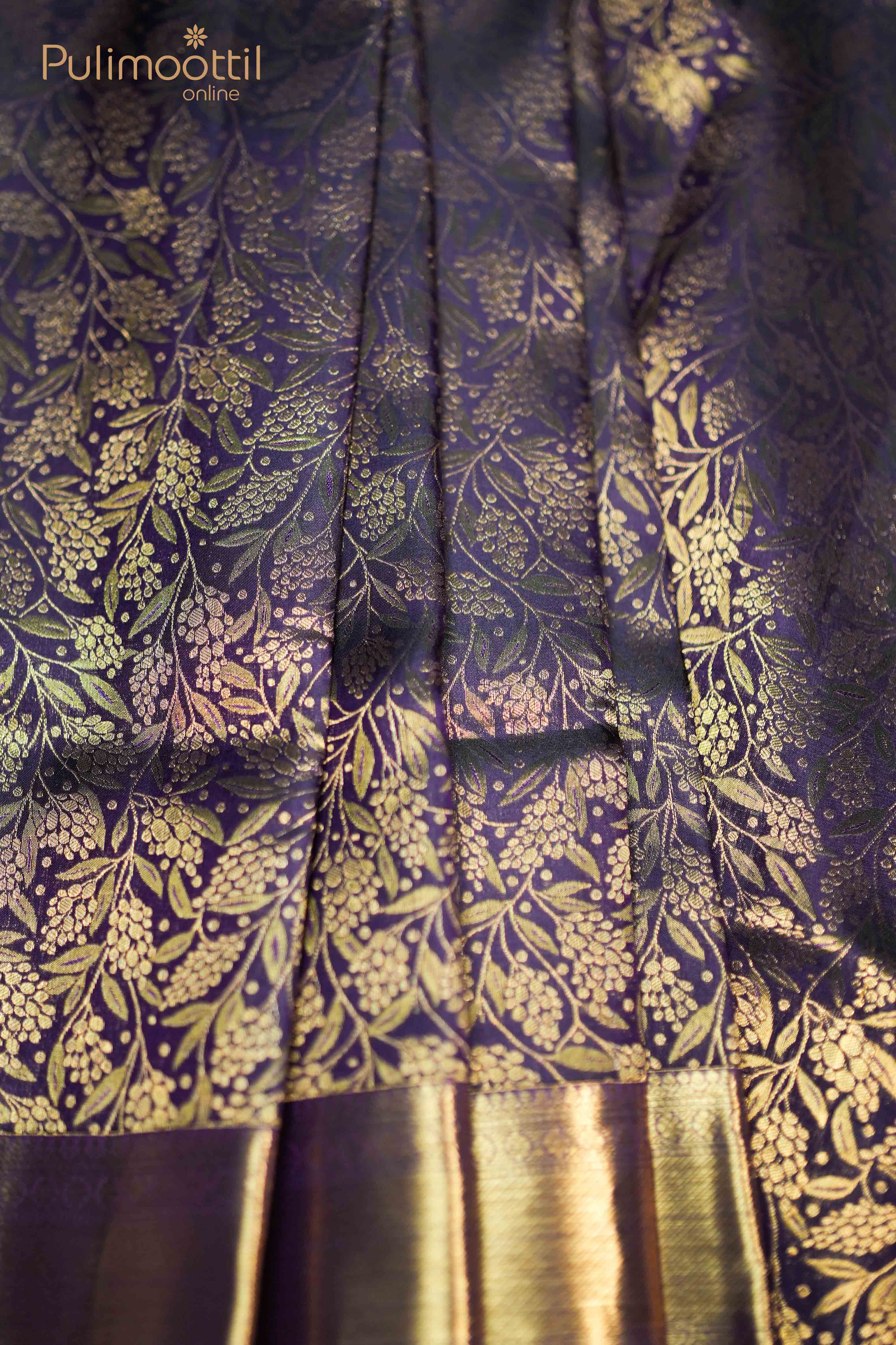 Close-up of dark purple Kanchipuram saree featuring intricate gold floral brocade design with traditional golden border