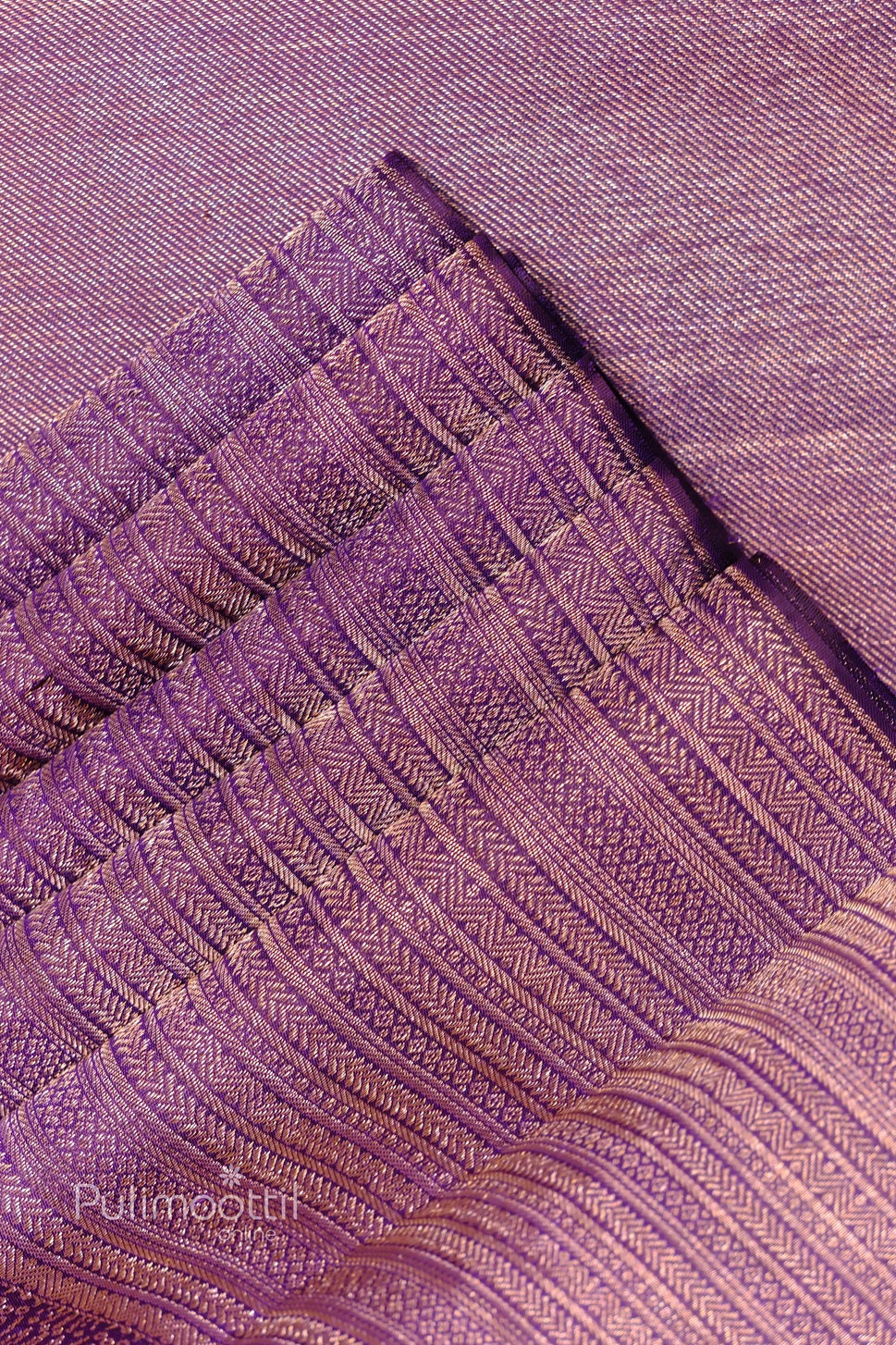 Close-up of dark purple Kanchipuram silk saree border with dense gold geometric zari brocade weave.
