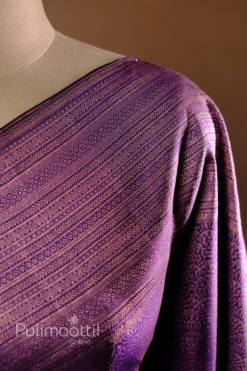 Swirled dark purple Kanchipuram silk saree showcasing smooth sheen and gold-zari highlights.

