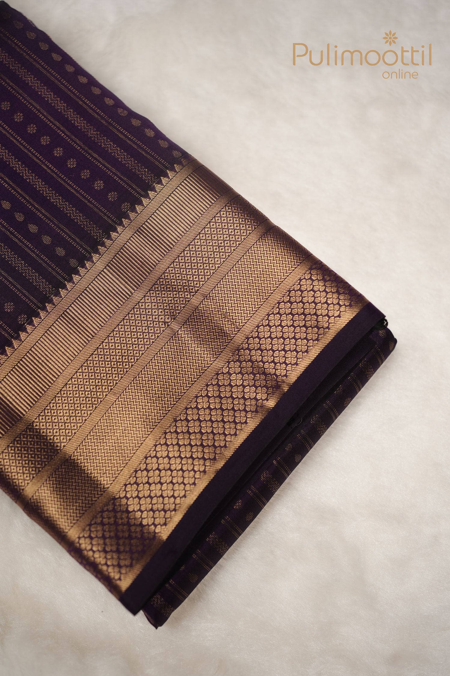 “Dark purple Kanchipuram silk saree with fine golden zari stripes and scattered small buttas on the body.