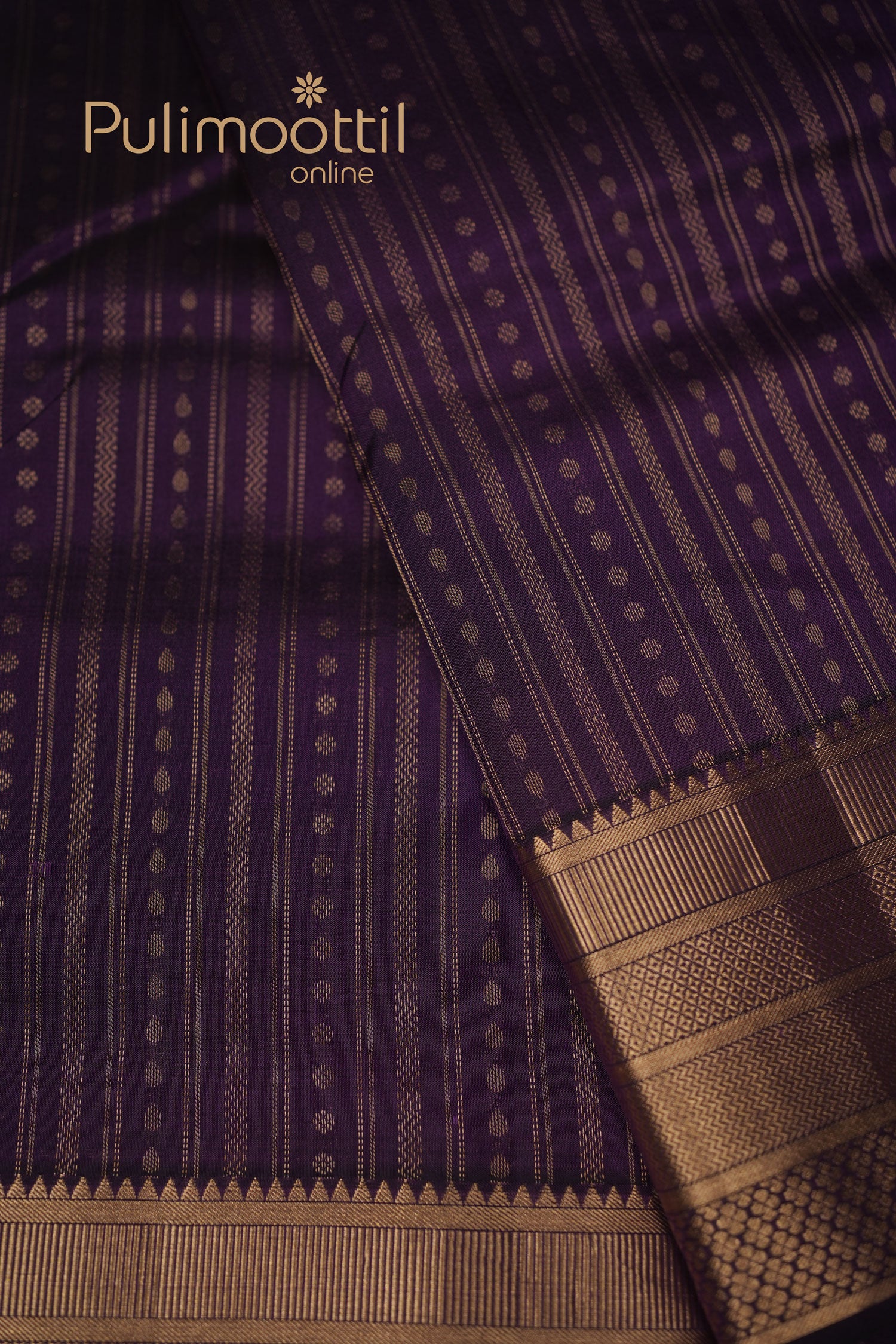 Dark purple Kanchipuram silk saree with fine golden zari stripes on the body and scattered small buttas, draped to reveal the intricate golden zari border and weave