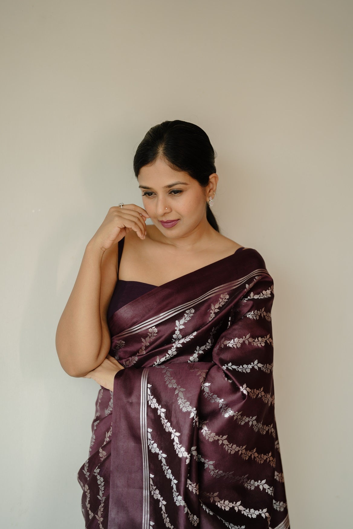 Woman in deep coffee mango silk saree with silver and golden zari floral design and plain border, styled for ethnic wear.