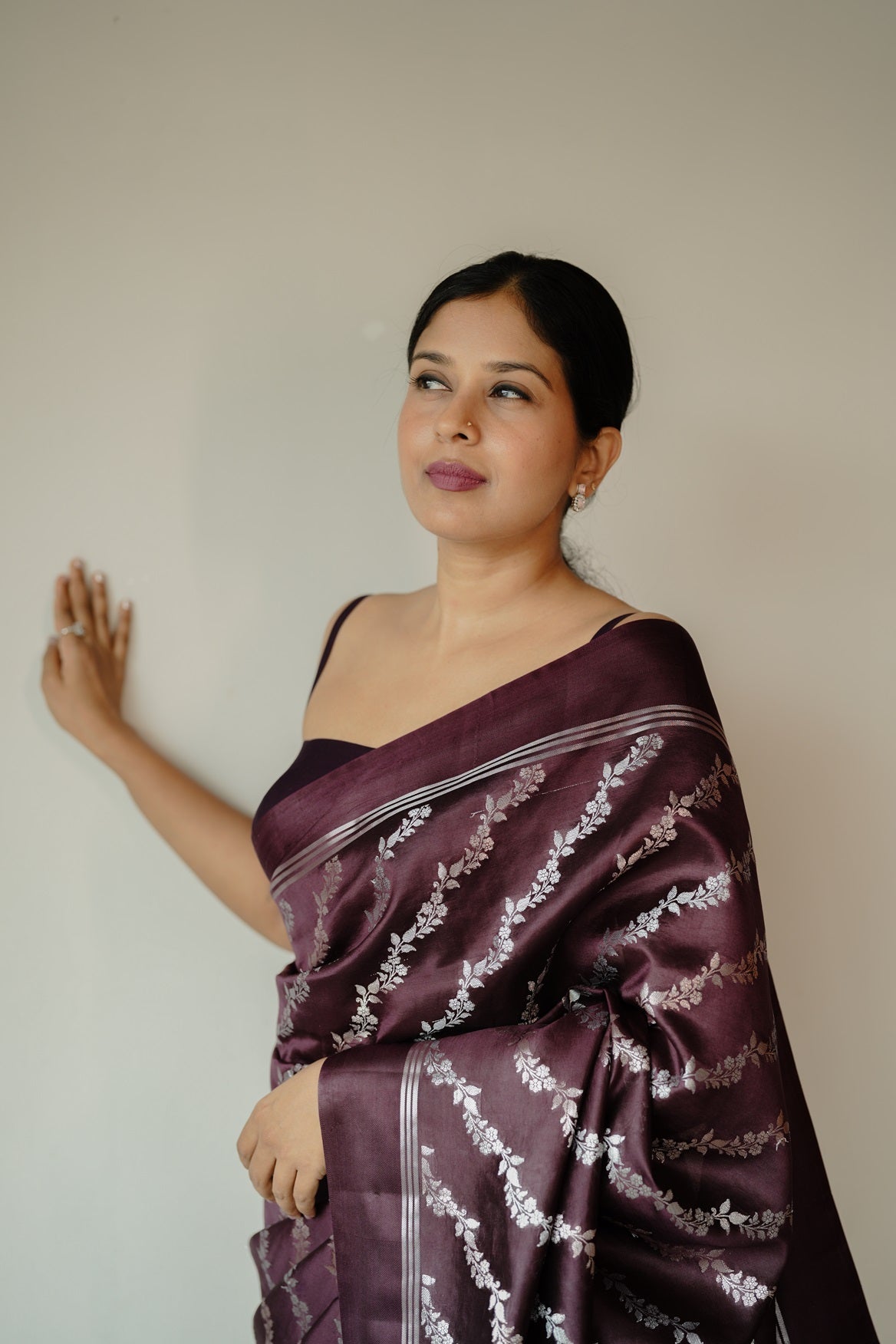 Woman in deep coffee mango silk saree adorned with silver and golden zari floral motifs, posing against a plain background.