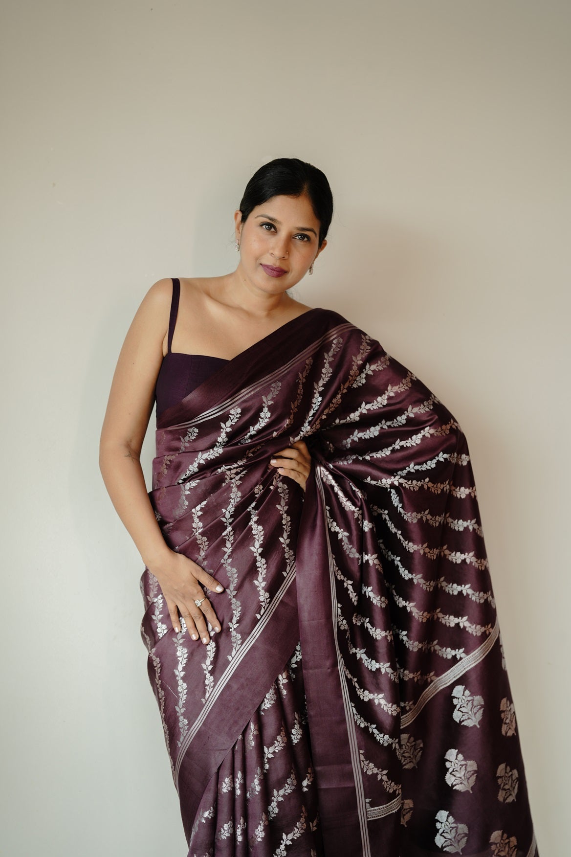 Woman in deep coffee mango silk saree adorned with silver and golden zari floral motifs, posing against a plain background.