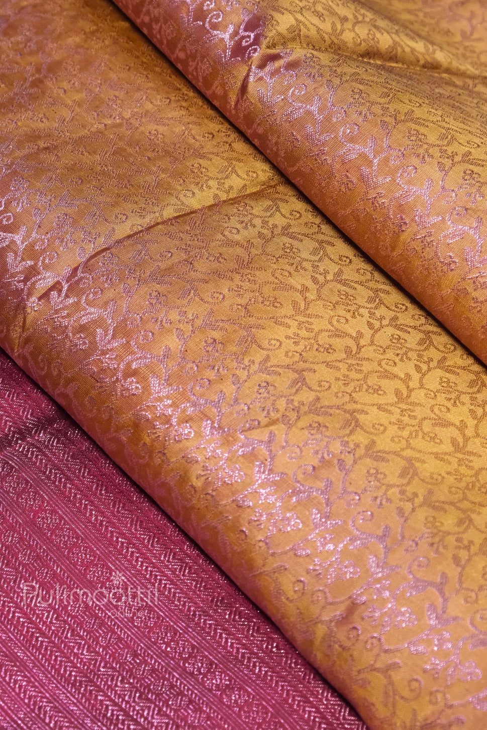 Luxurious silk saree fabric showing golden brocade patterns with intricate floral motifs and maroon border