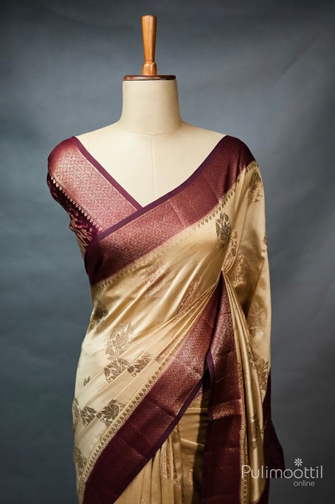 Ecru beige Chiniya Banarasi silk saree with maroon contrast Banarasi thread floral design and geometrical patterned border, displayed on a mannequin