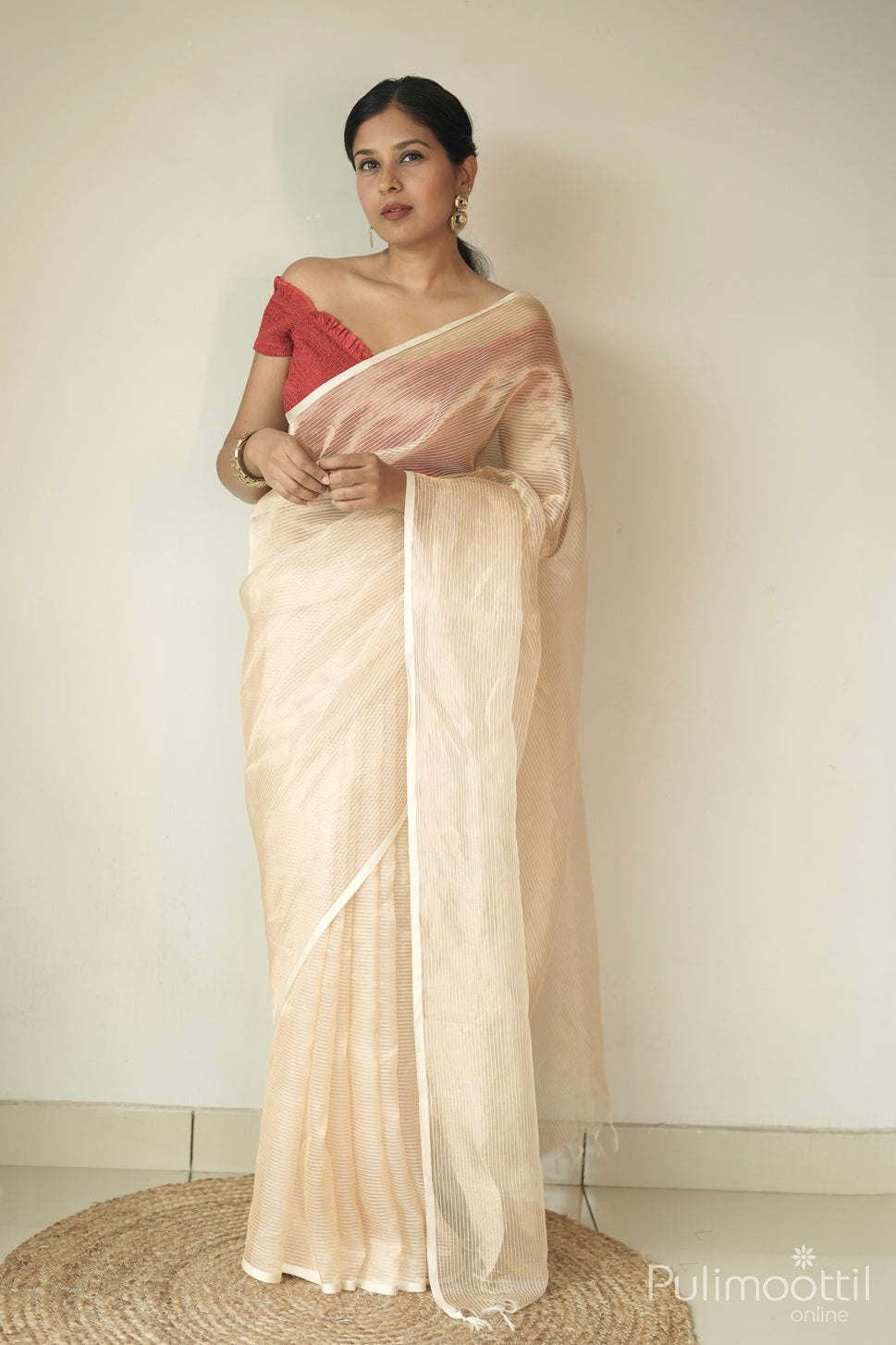Golden tissue organza saree with vertical stripes and small border, draped on model with tassel pallu.