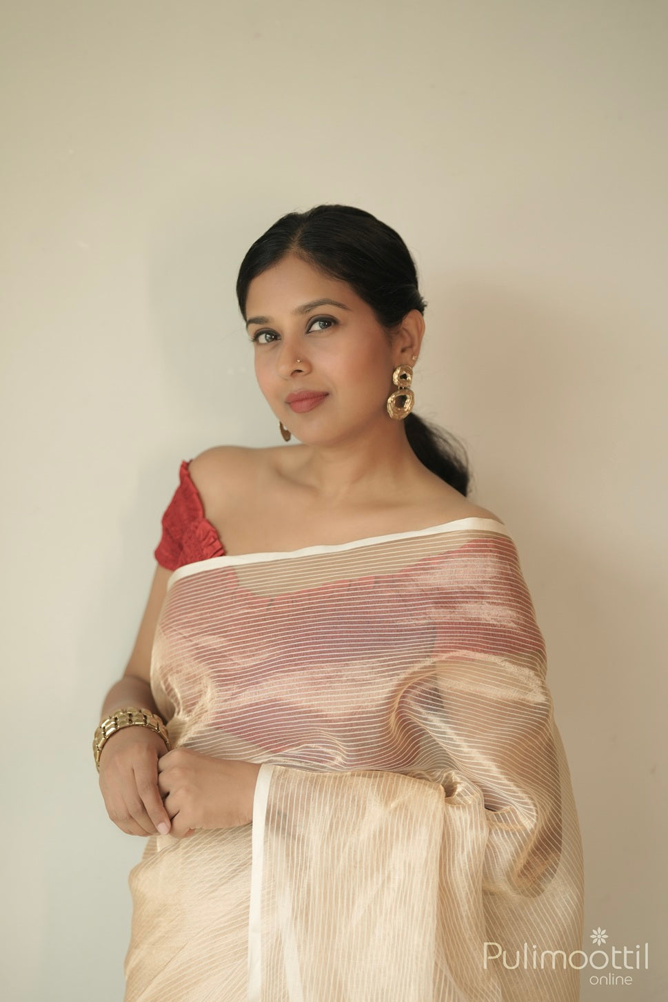 Golden tissue organza saree close-up showing vertical striped pattern on upper drape.