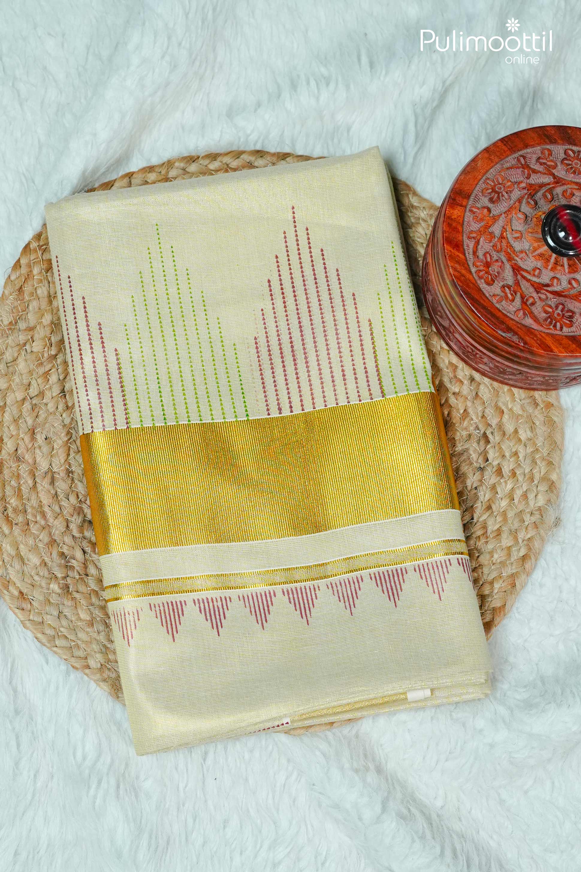 Folded golden tissue Kerala set saree with temple design print in red and green threads, paired with golden tissue border, displayed on woven mat — traditional Onam saree