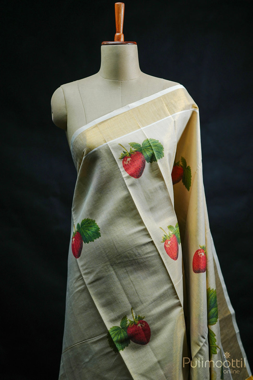 Golden tissue kasavu saree with plain sheen body and strawberry-pink fruit print near the border.
