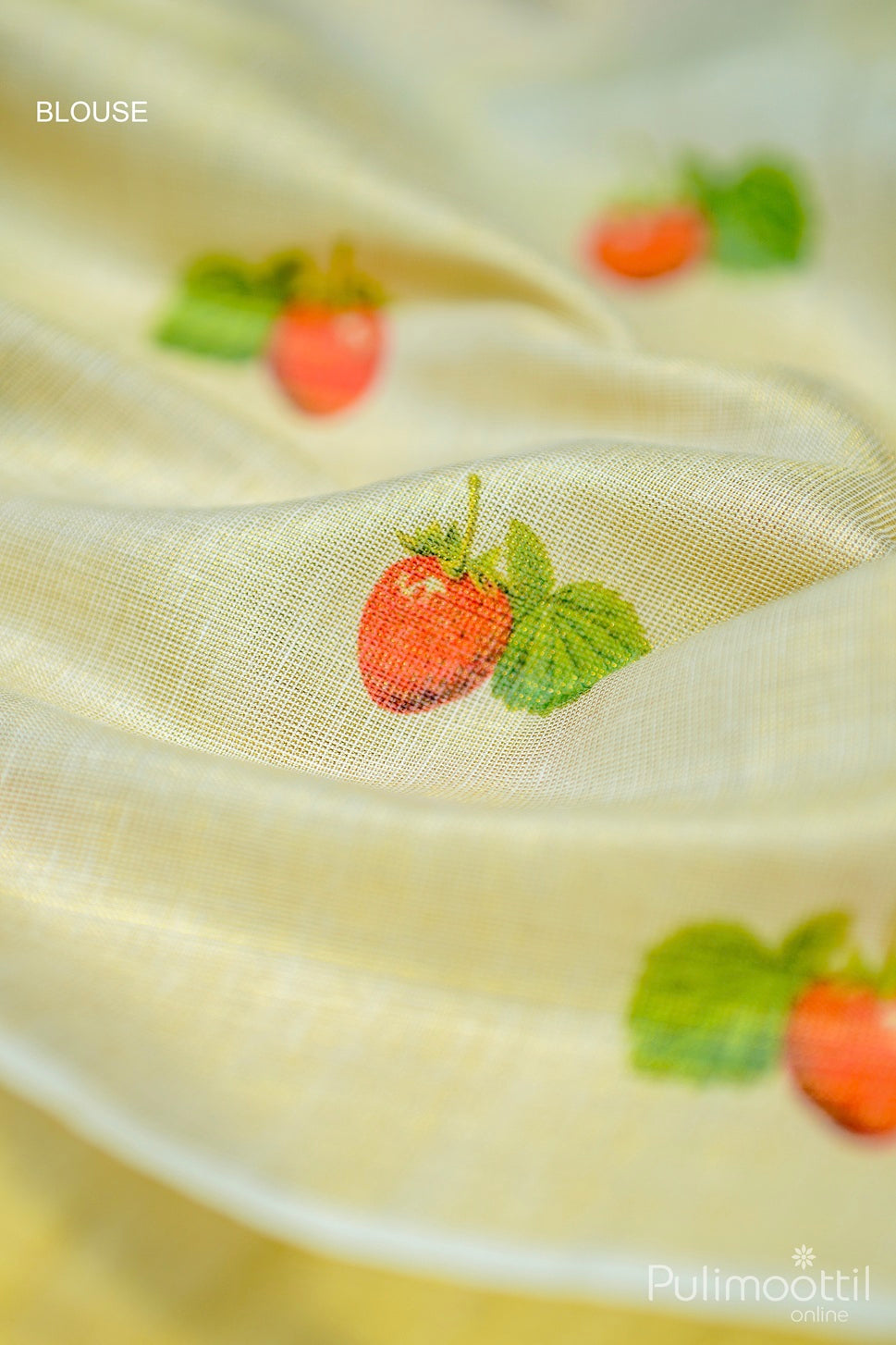 Blouse piece close-up with small red strawberry and single green leaf printed near border.

