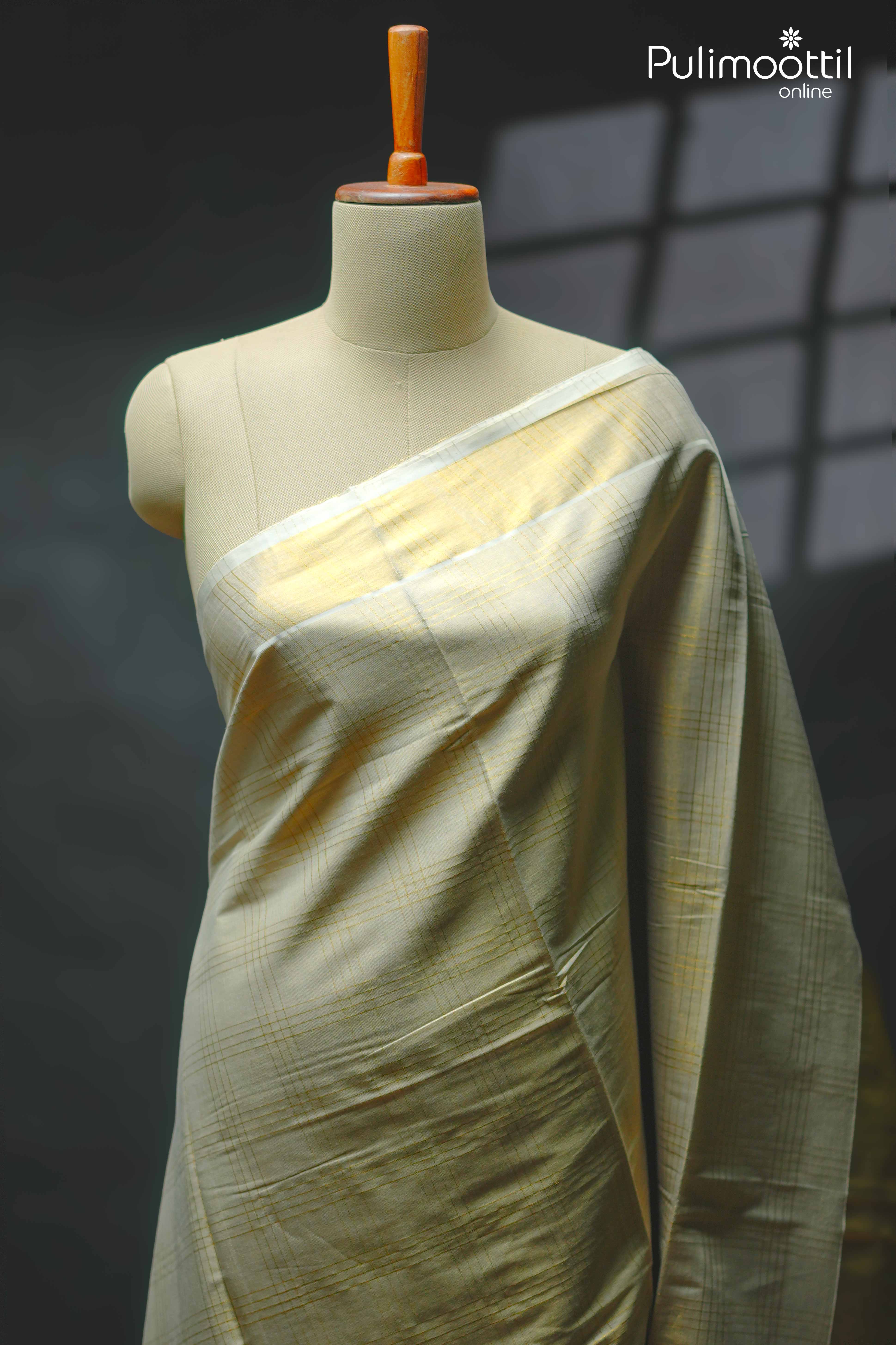 Golden Zari check design tissue saree draped on a mannequin, featuring subtle golden checked patterns on a cream tissue fabric with matching border and pallu – traditional Kerala set saree style.