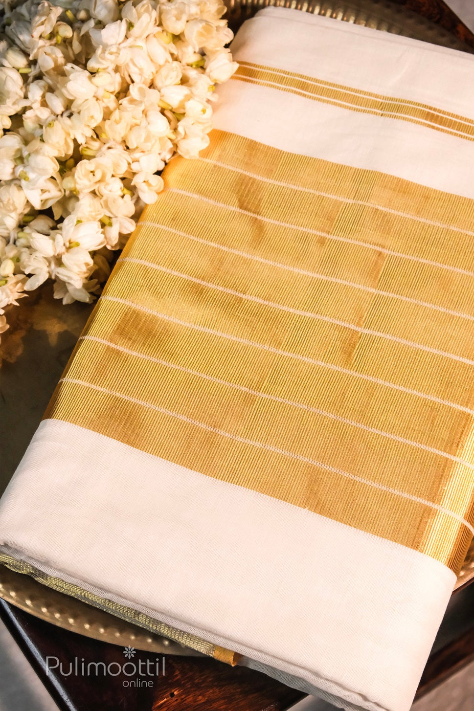 Close-up of white Kerala saree with golden zari stripes in vertical pleats