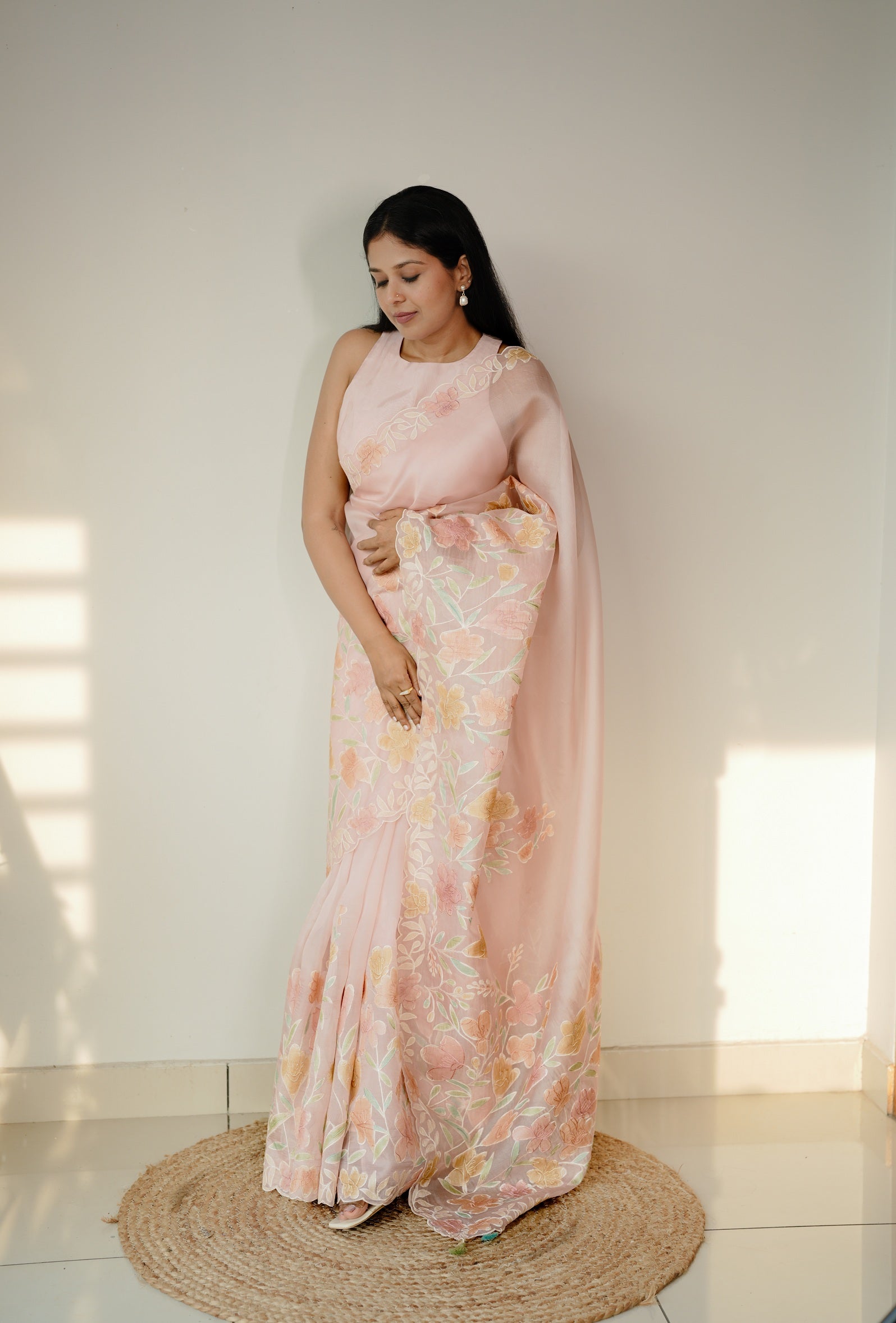 Model wearing a sheer silk organza ensemble with handpainted floral motifs and delicate appliqué details; soft pastel hues create an ethereal, romantic aesthetic.