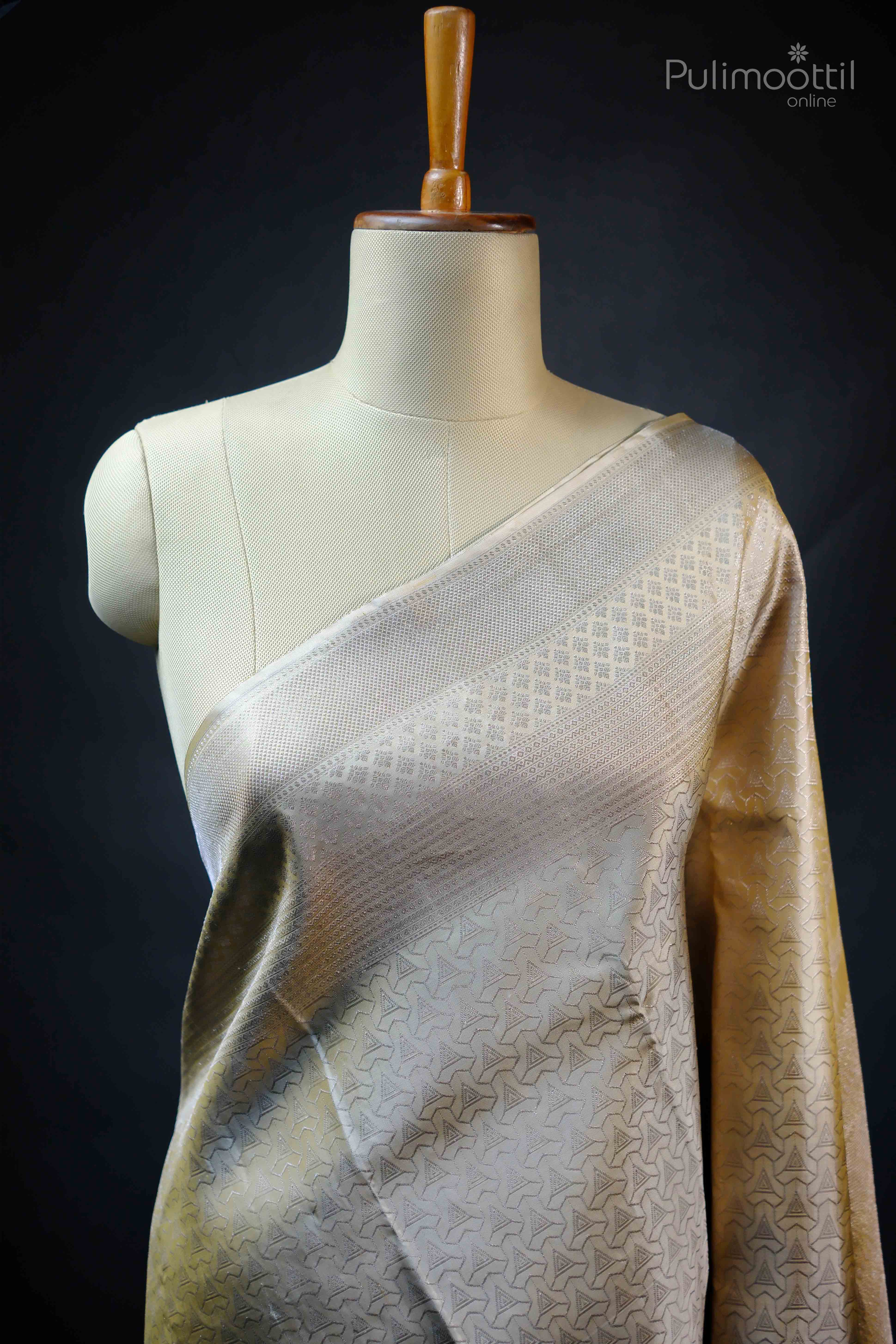 Ivory Kanchipuram silk saree draped on mannequin showing intricate triangle motifs and designer border.