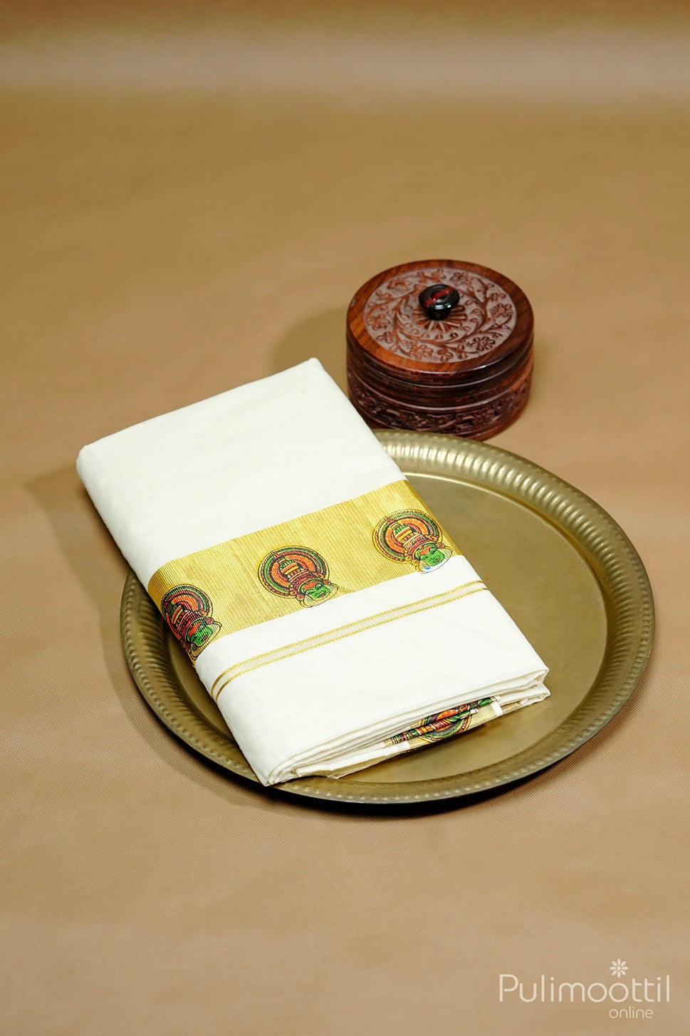 Kerala cotton set saree with Kathakali print border placed on brass plate