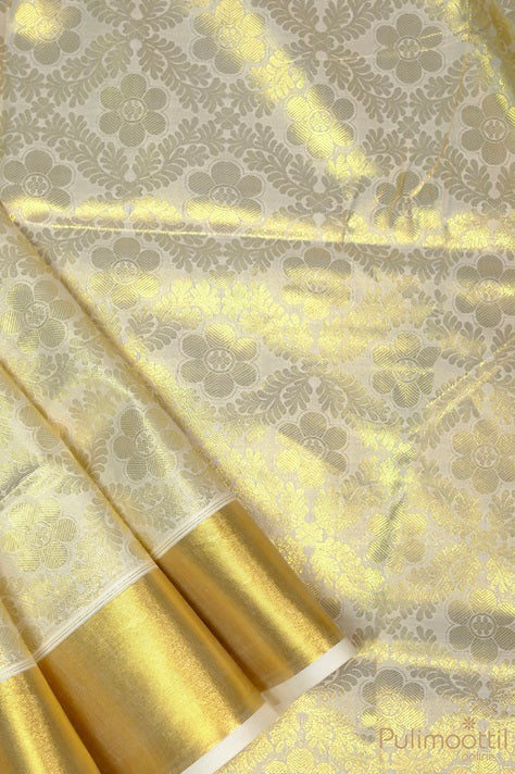 Kerala brocade saree body with gold zari floral designs and golden tissue border on cream base.