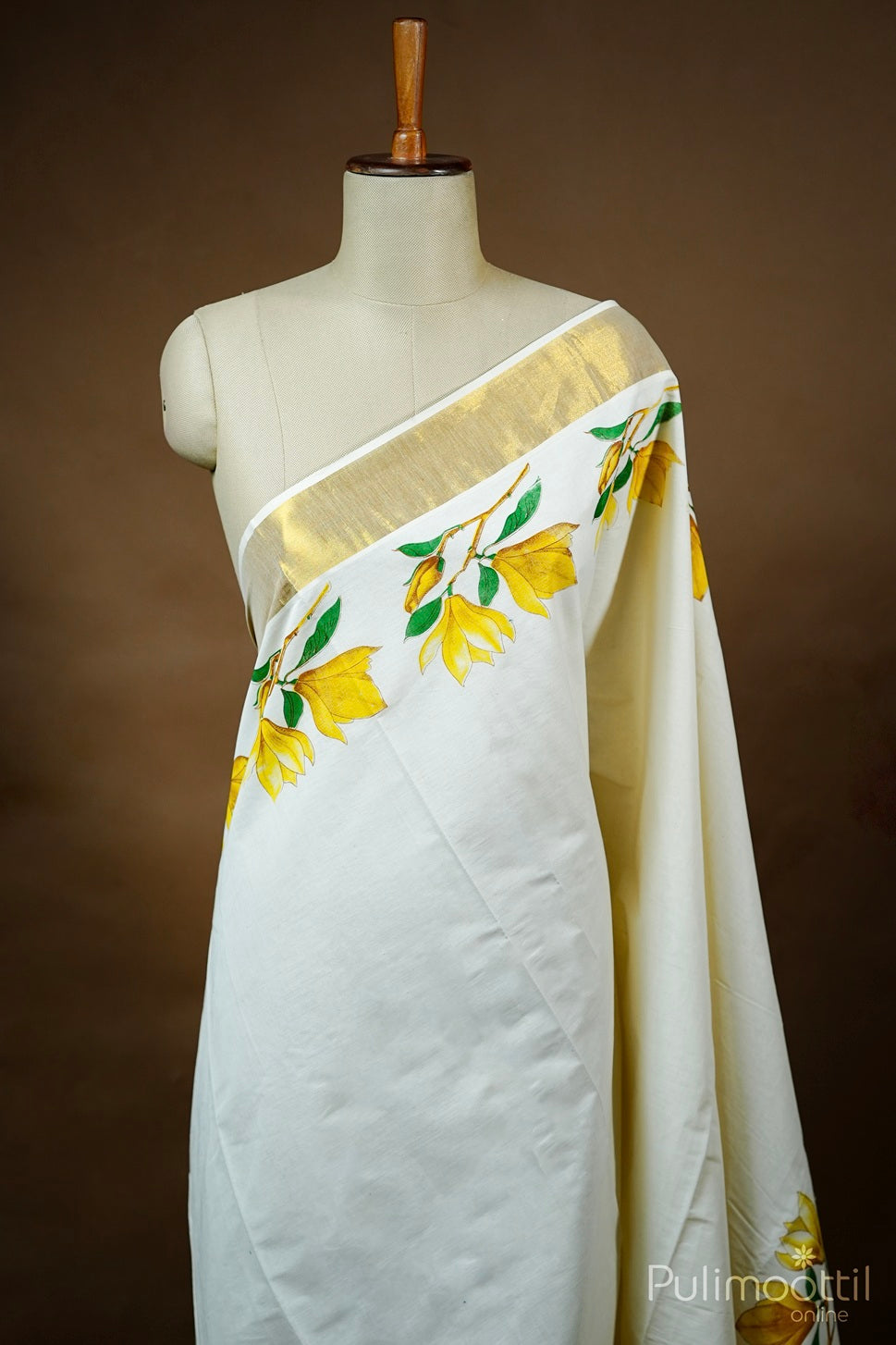 Off white Kerala saree with yellow floral print and golden tissue border draped on mannequin