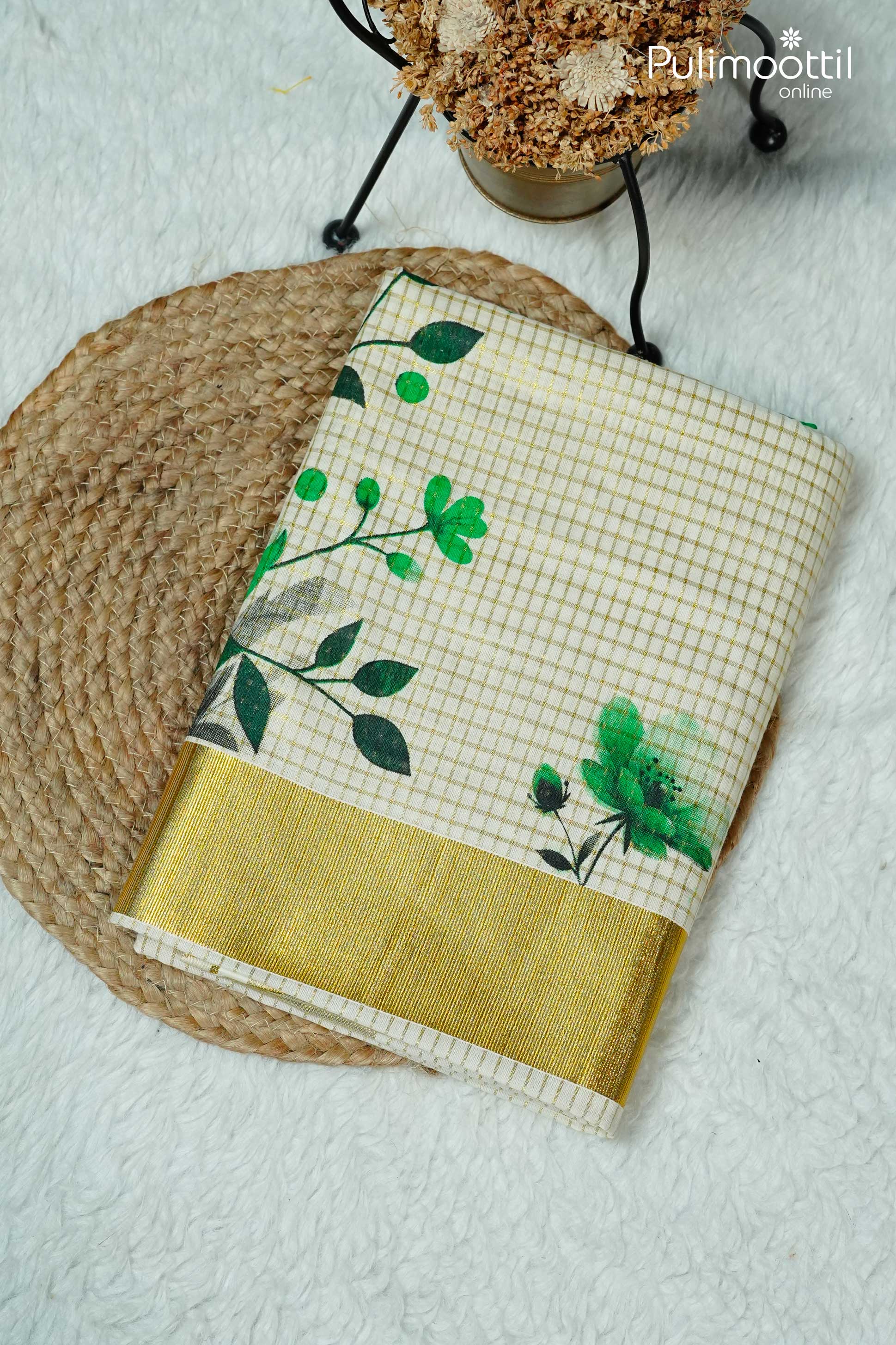 Folded Kerala traditional set saree with golden zari check and green floral design, finished with shimmering golden tissue border, placed on woven mat with decorative flowers.