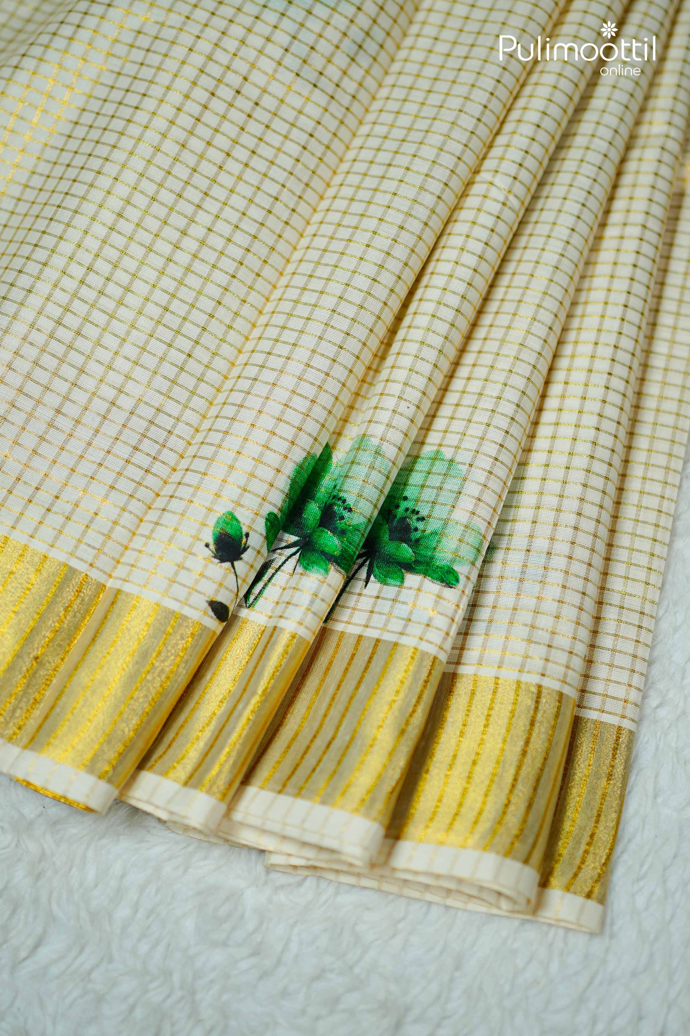Cream Kerala tissue saree blouse piece with golden zari checked pattern, green floral motif, and gold striped border.